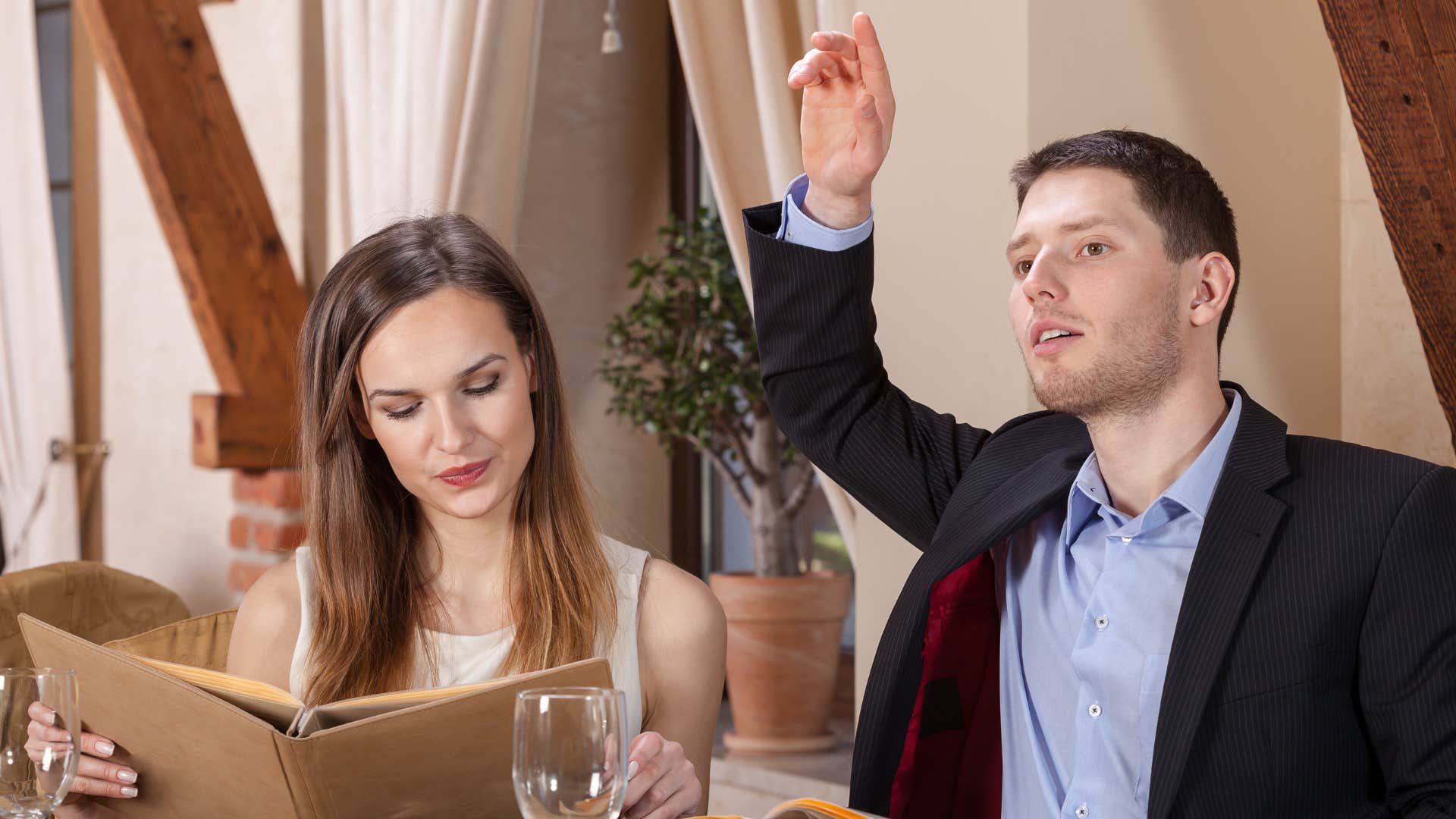 a man waves down his server in a busy restaurant
