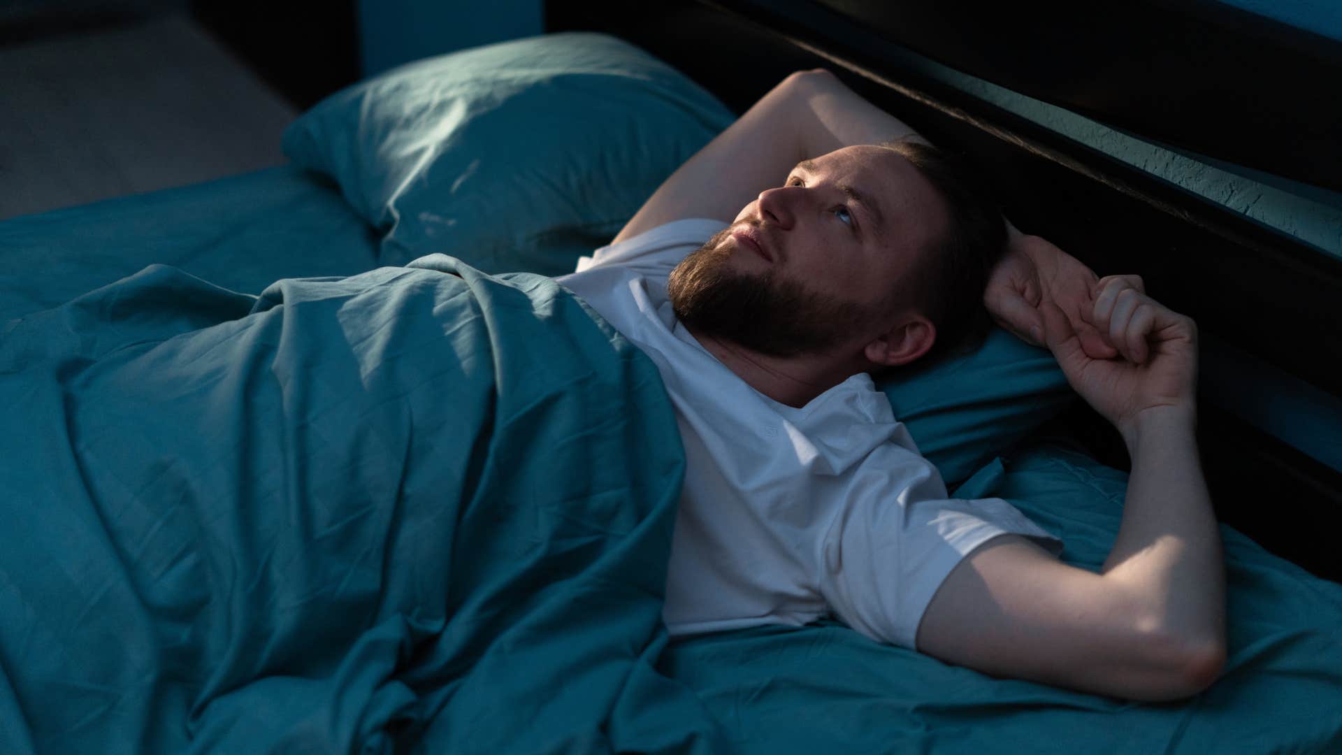 man tired in bed from unhealthy sleep schedule