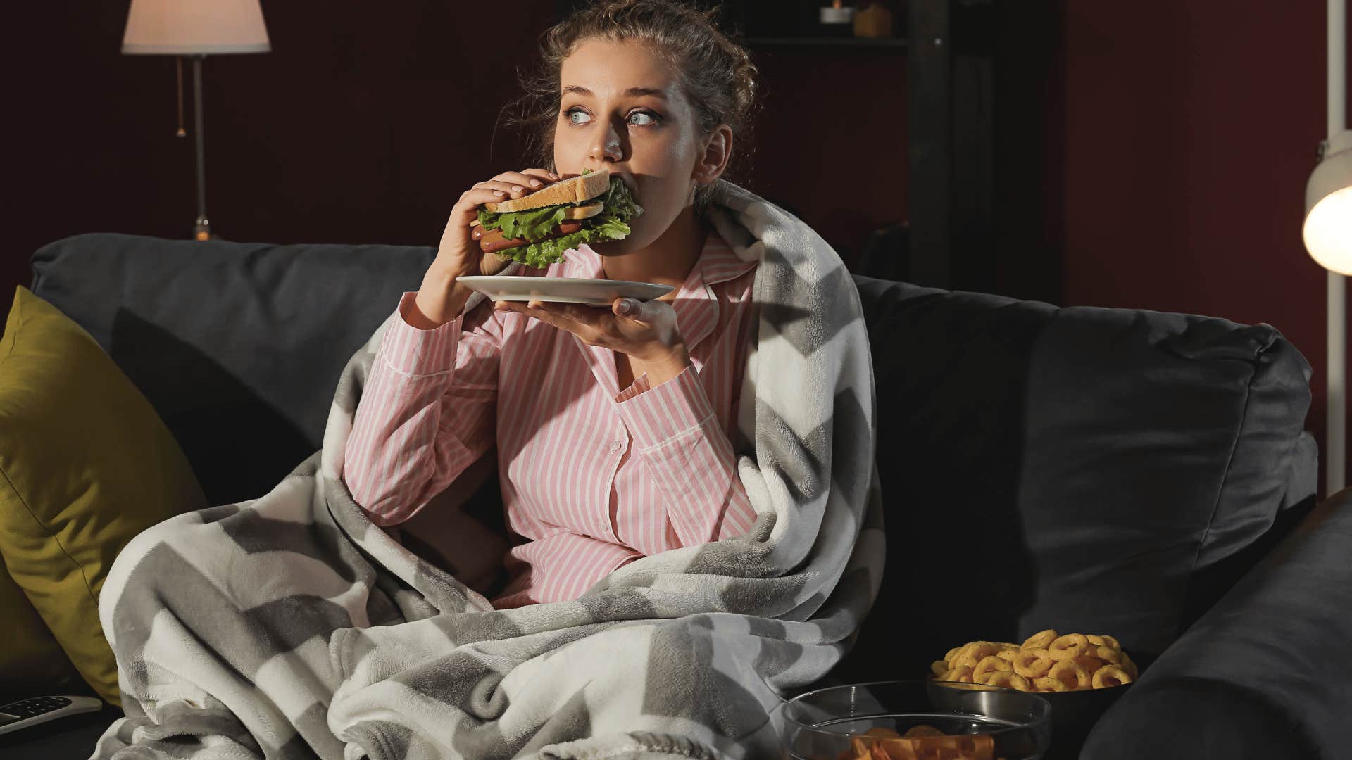 young woman over-consuming food on couch