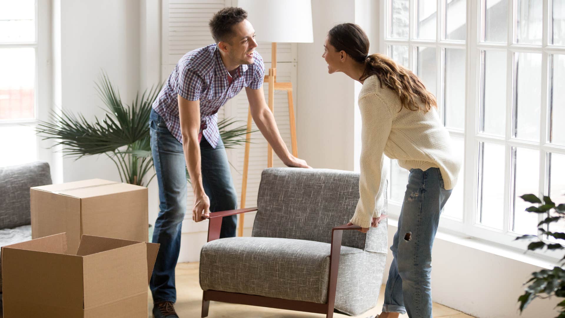 a couple lifts a heavy chair together to move it across the room