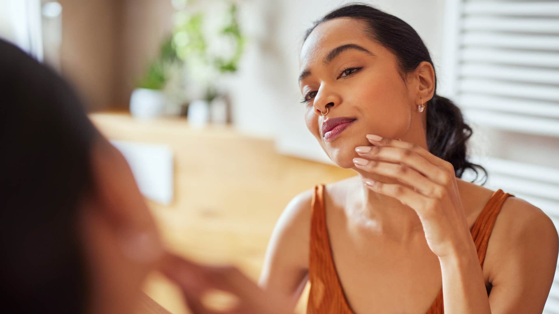 a woman looks at her clean and hydrated skin