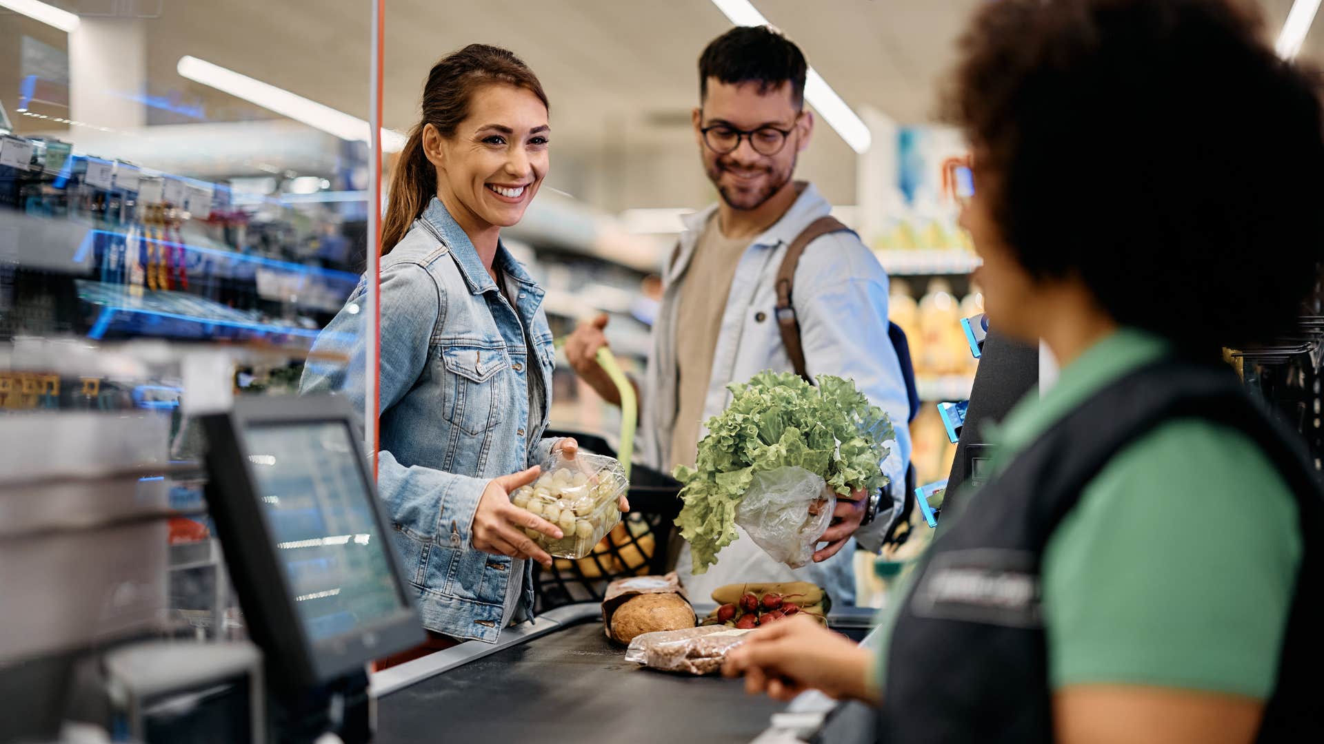 woman paying with cash smiling at grocery store checkout
