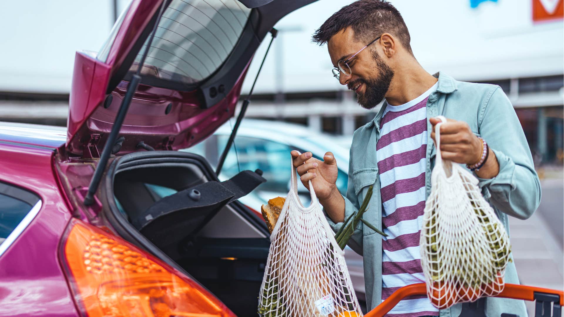 man putting reusable grocery bags into his car