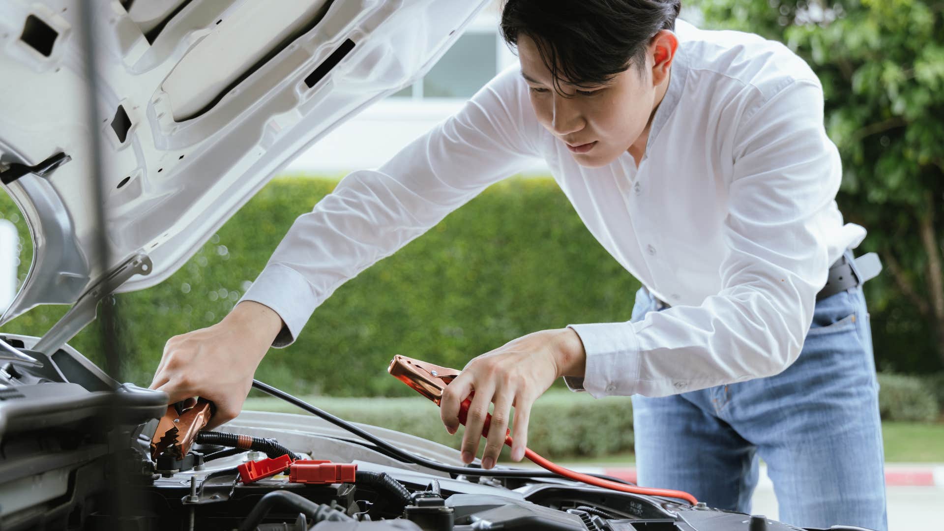 a man uses the jumper cables he keeps in his car to restart his car