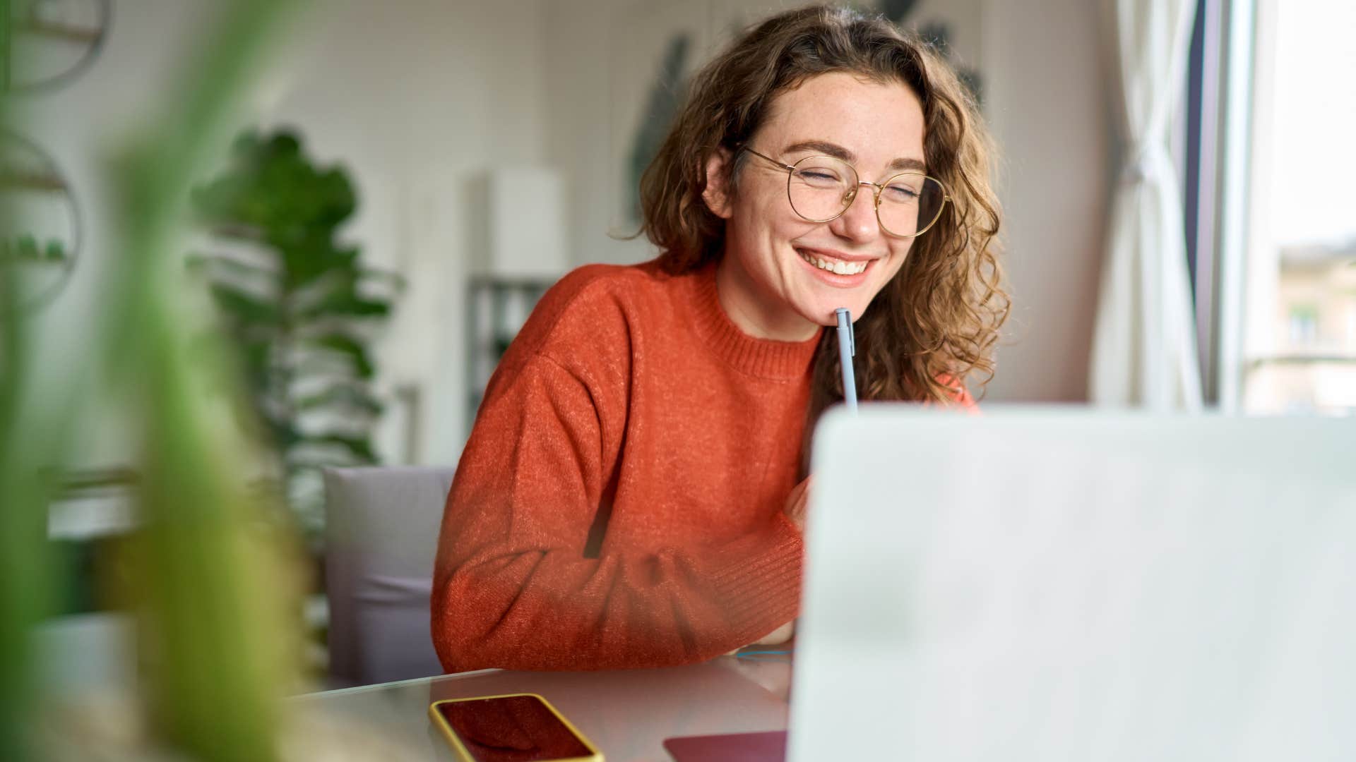 woman smiling at laptop sending emails