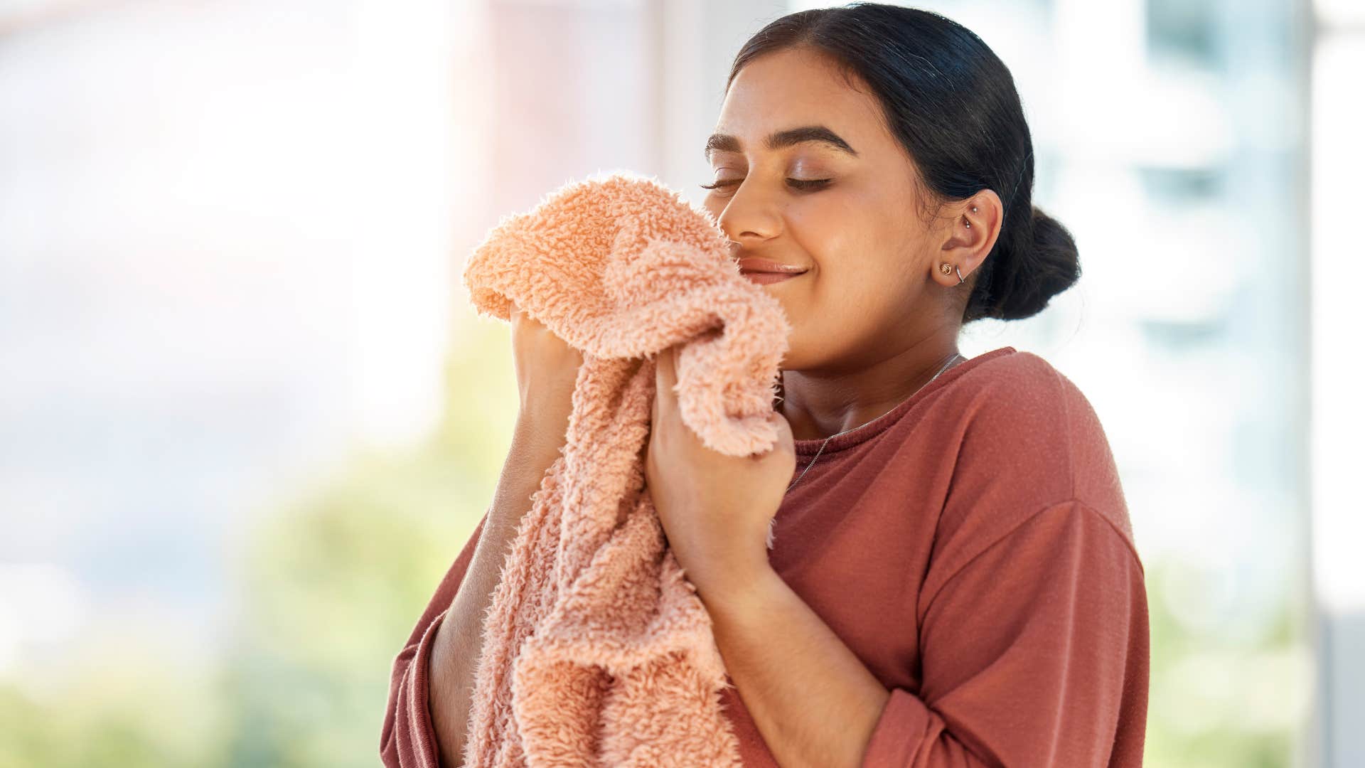 gen z woman smiling and smelling mismatched towels