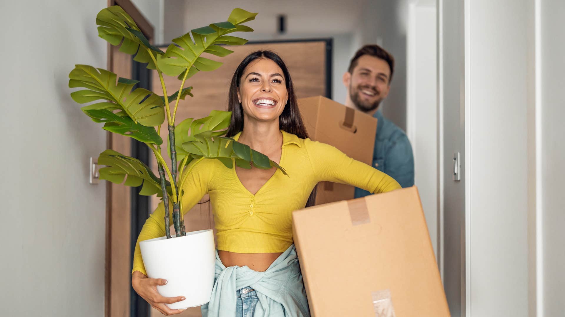 Gen Z couple moving into a house holding plants
