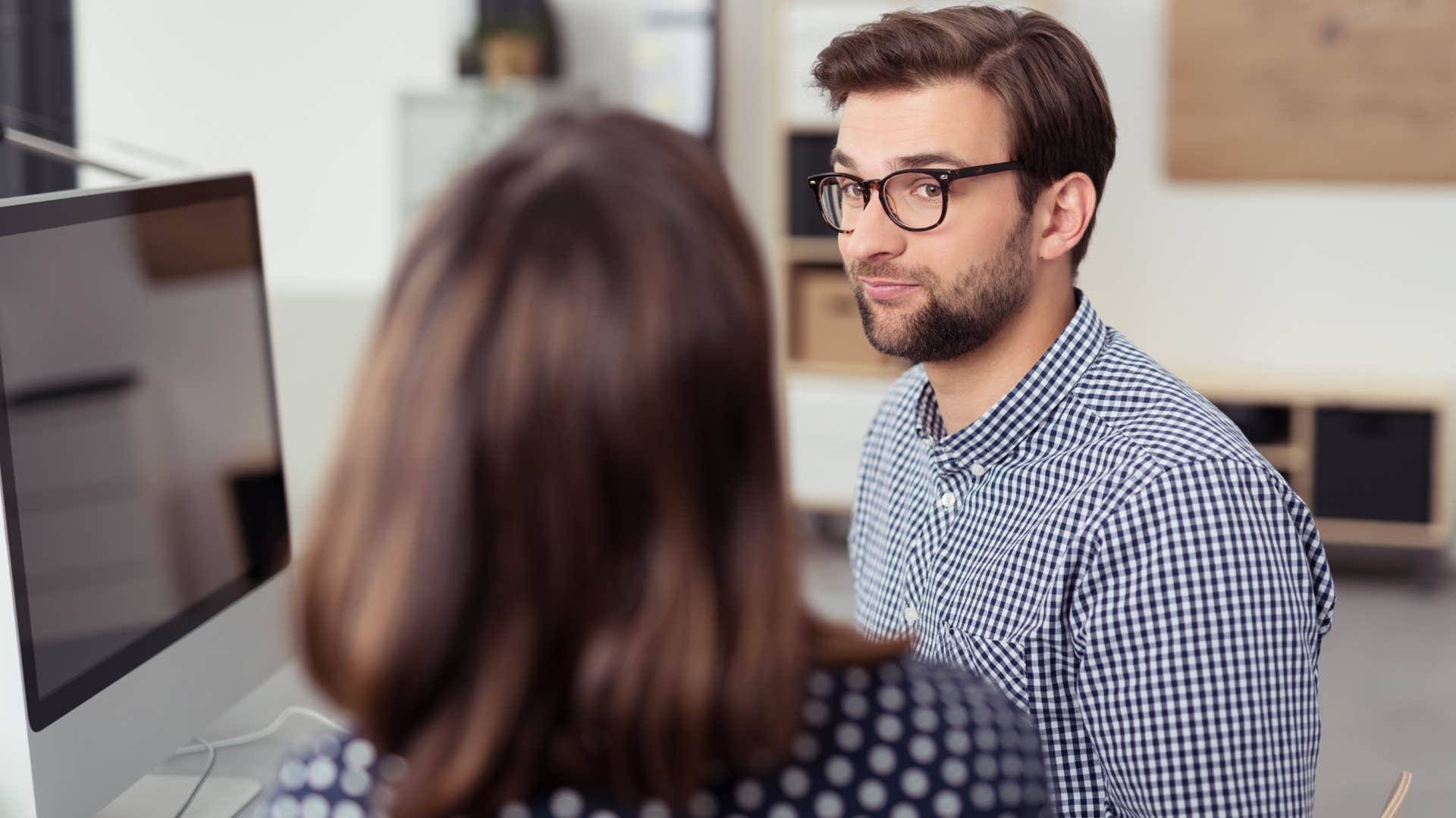 Gossipy man talking to a co-worker in the office.