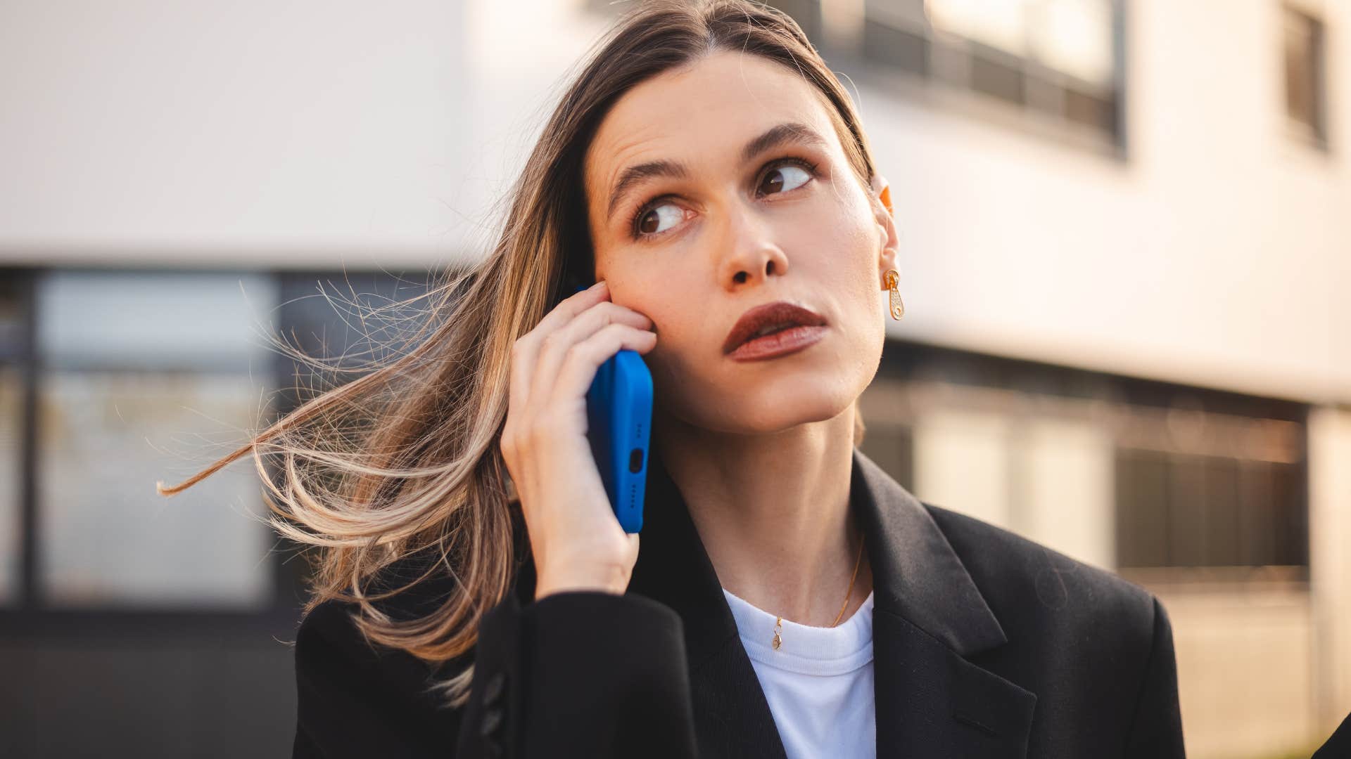 Woman who's not curious talking on the phone outside.