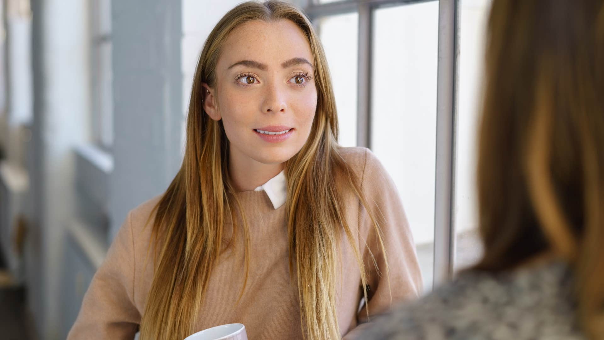 Woman who parrots everyone else's opinions looking at a friend.