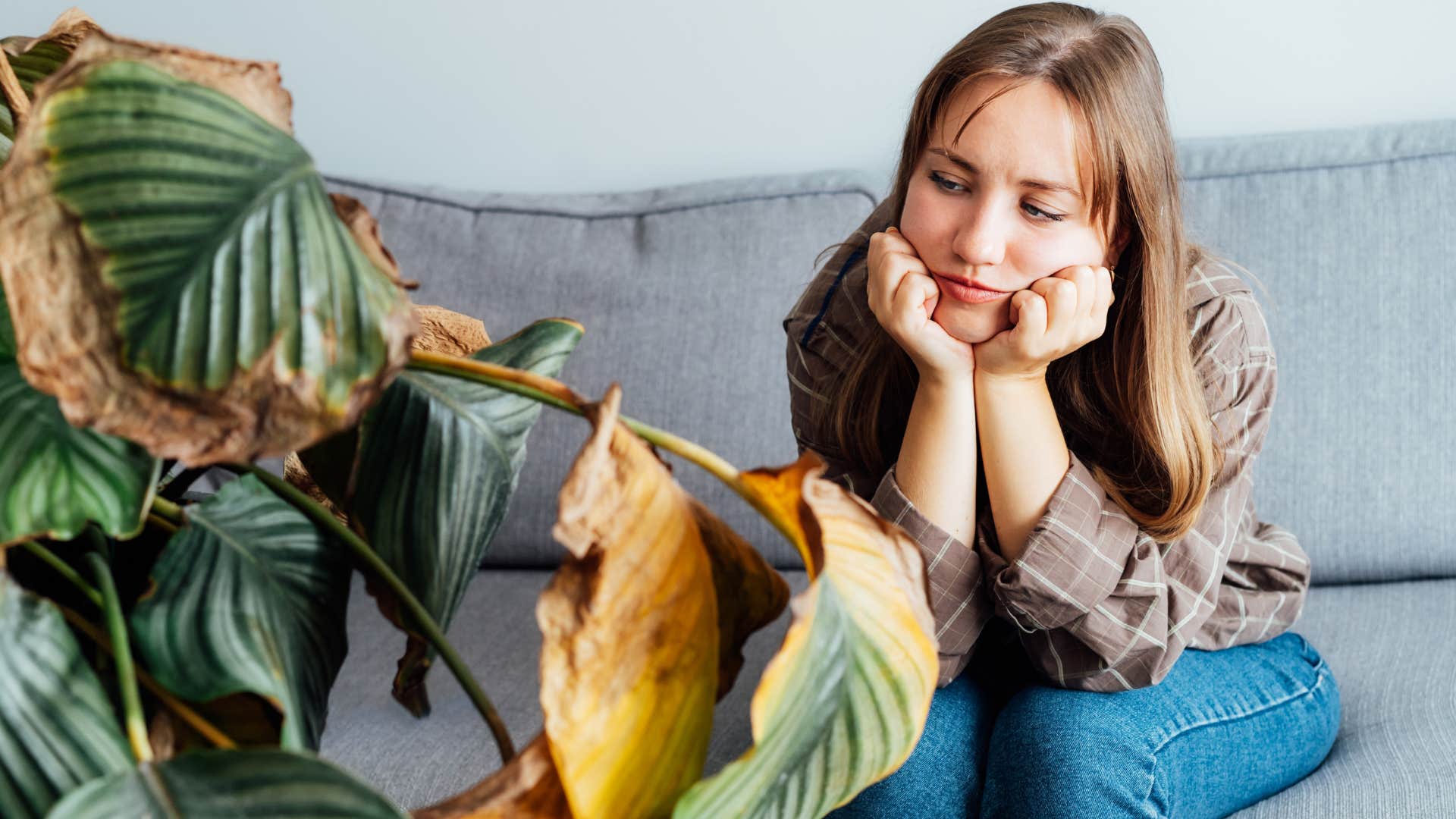 emotionally exhausted woman who has lost interest in hobbies looking at a dead plant