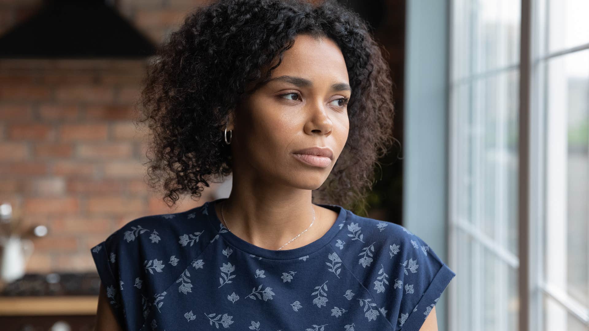 emotionally exhausted woman avoiding thinking about the future while looking out a windowf