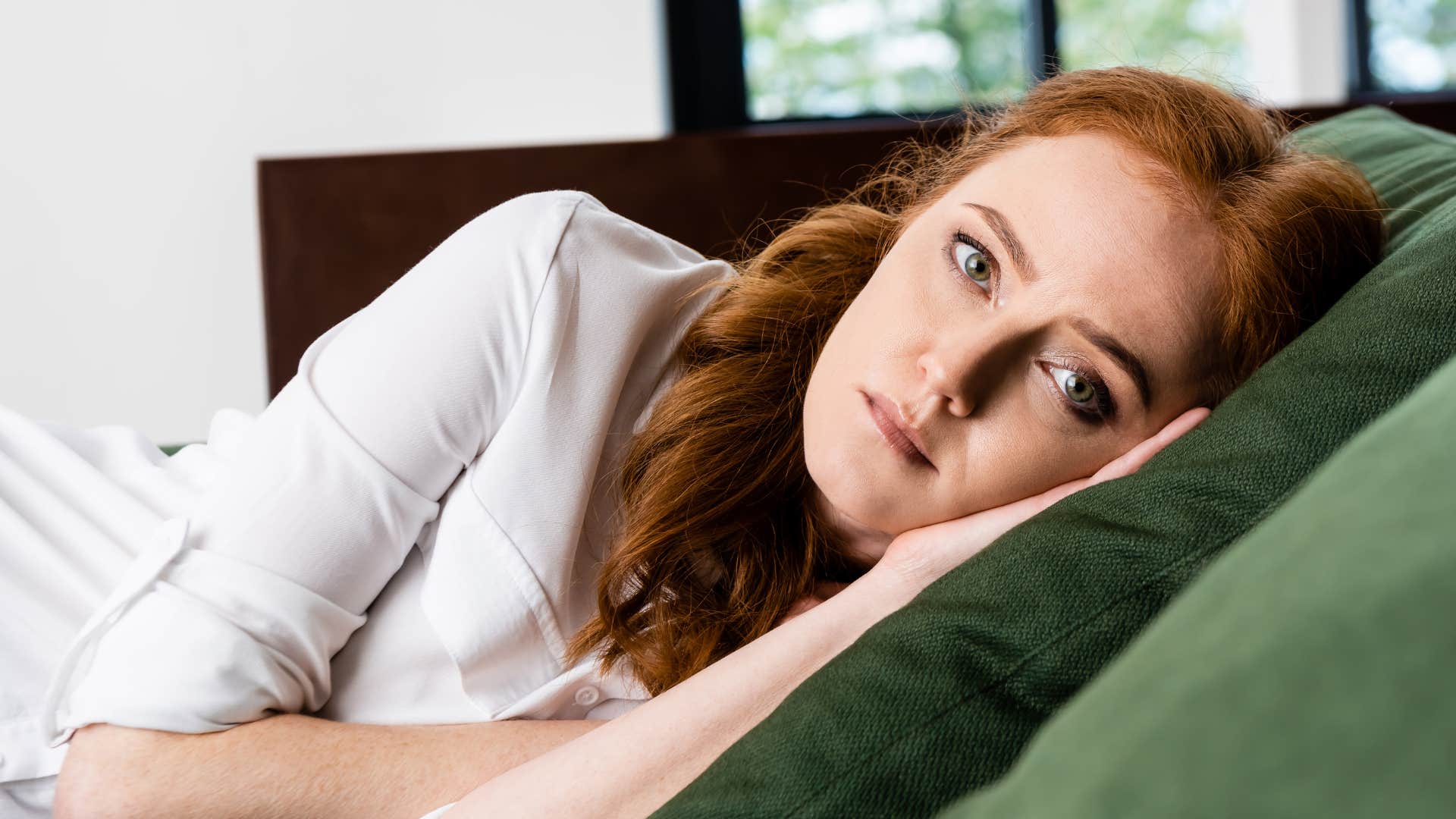 emotionally exhausted woman avoiding work while laying on her couch