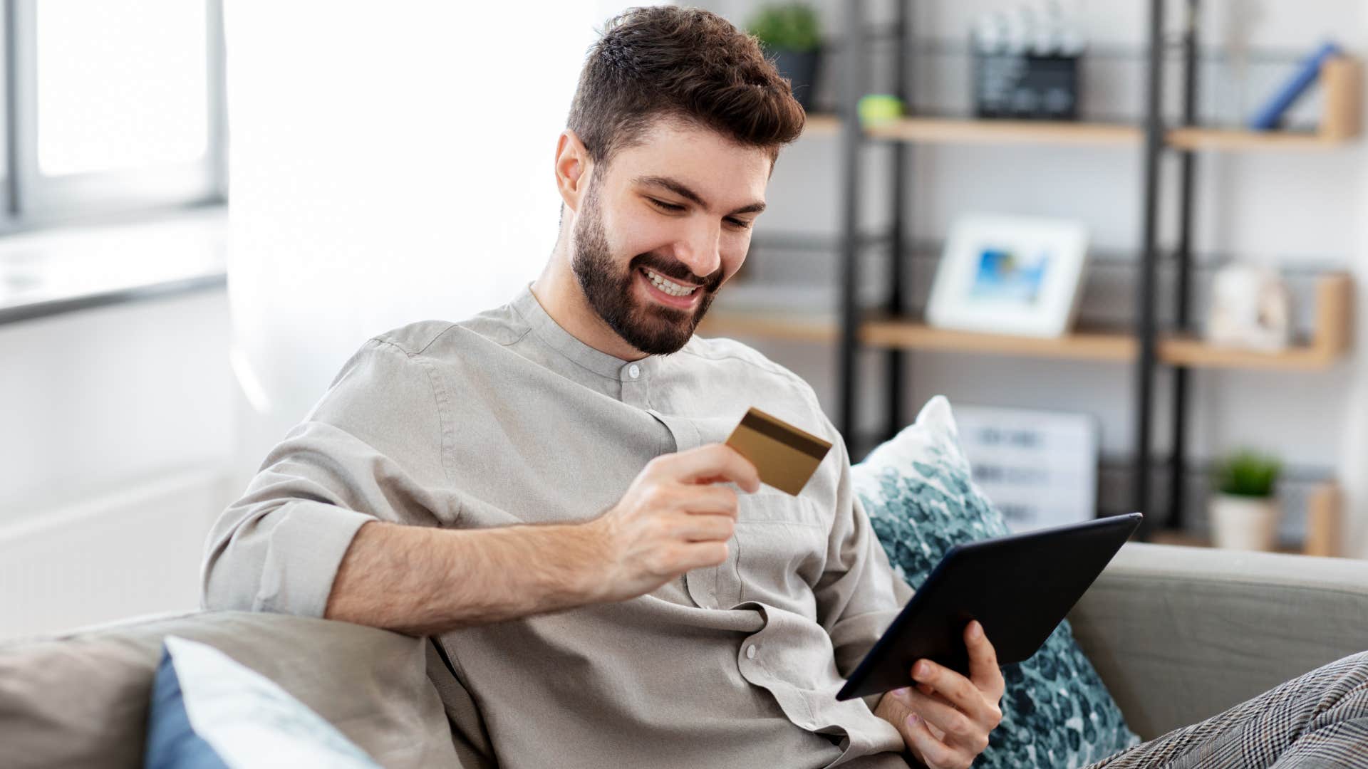 Man smiling and online shopping at home.