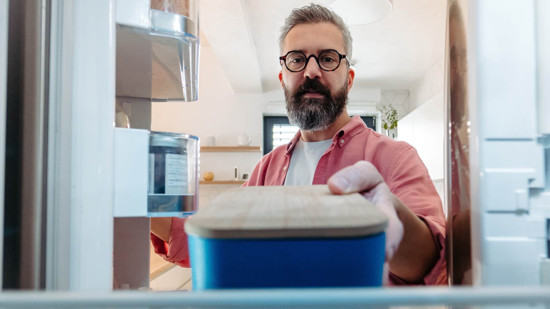 Man putting food containers in the fridge.