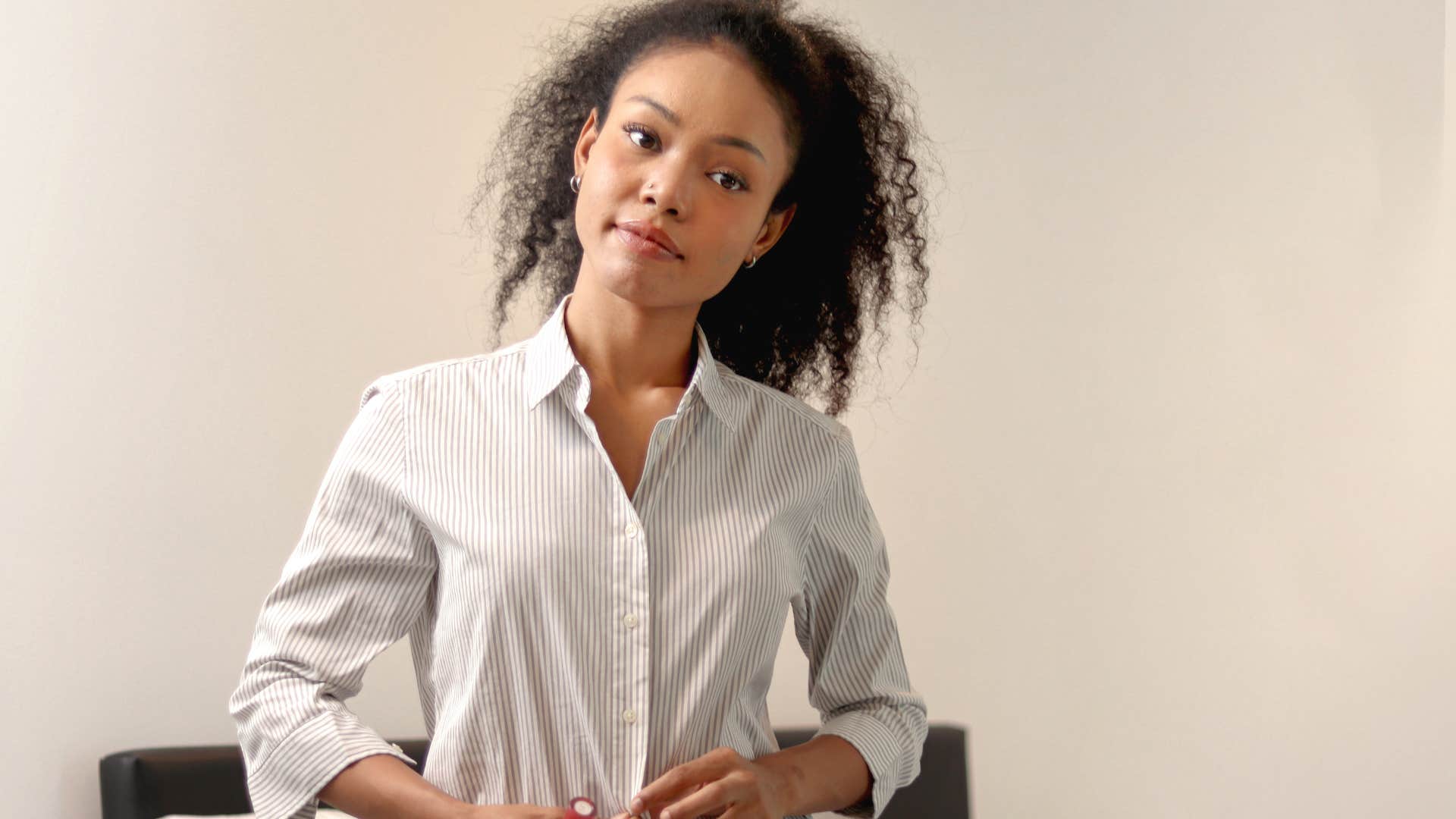 Woman smiling and getting dressed in quality clothing at home.