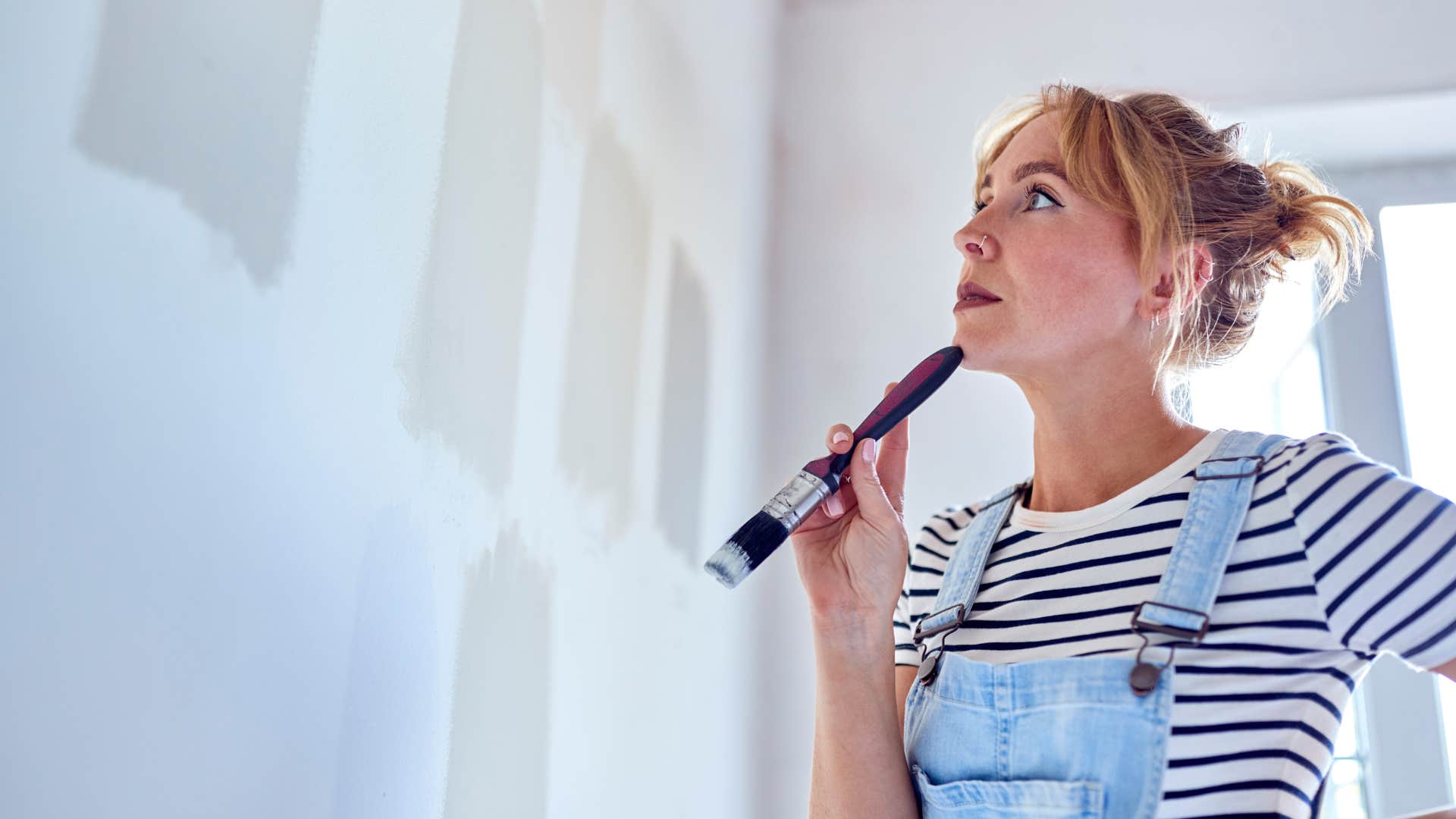 woman repainting wall after paint chipping