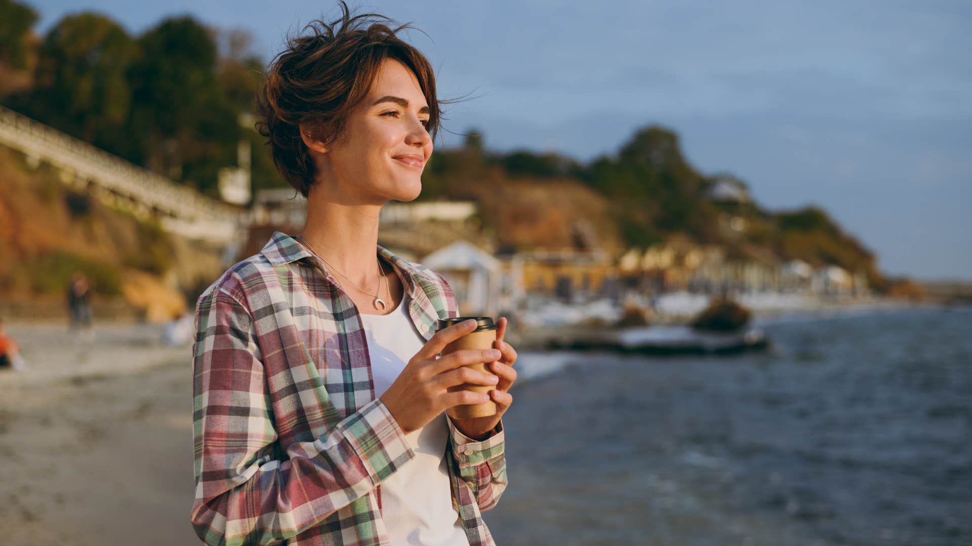 woman in white shirt holding cup of coffee as she went on her daily coffee shop run