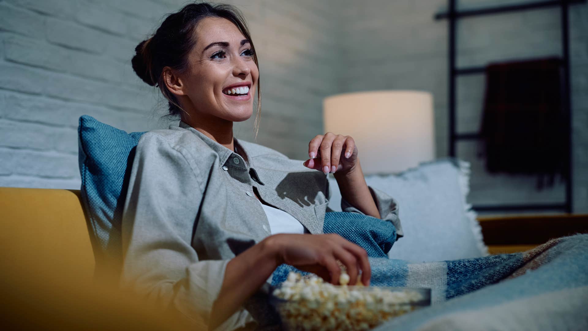 woman enjoying her subscription services as she watches tv while eating popcorn