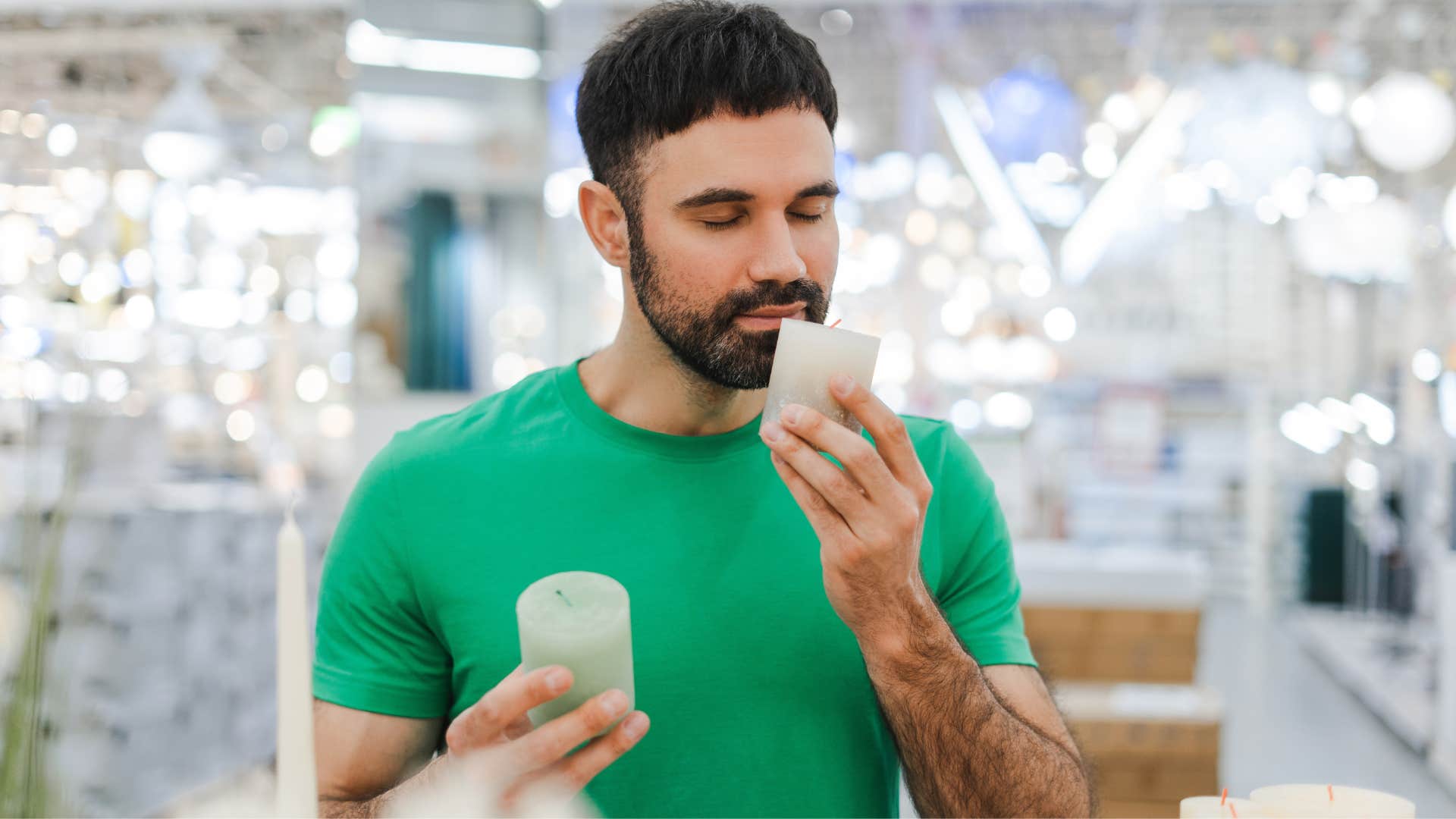 man smelling candles at store