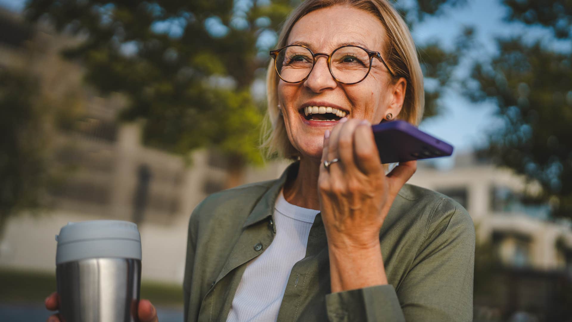 woman carrying thermos and talking on phone outside
