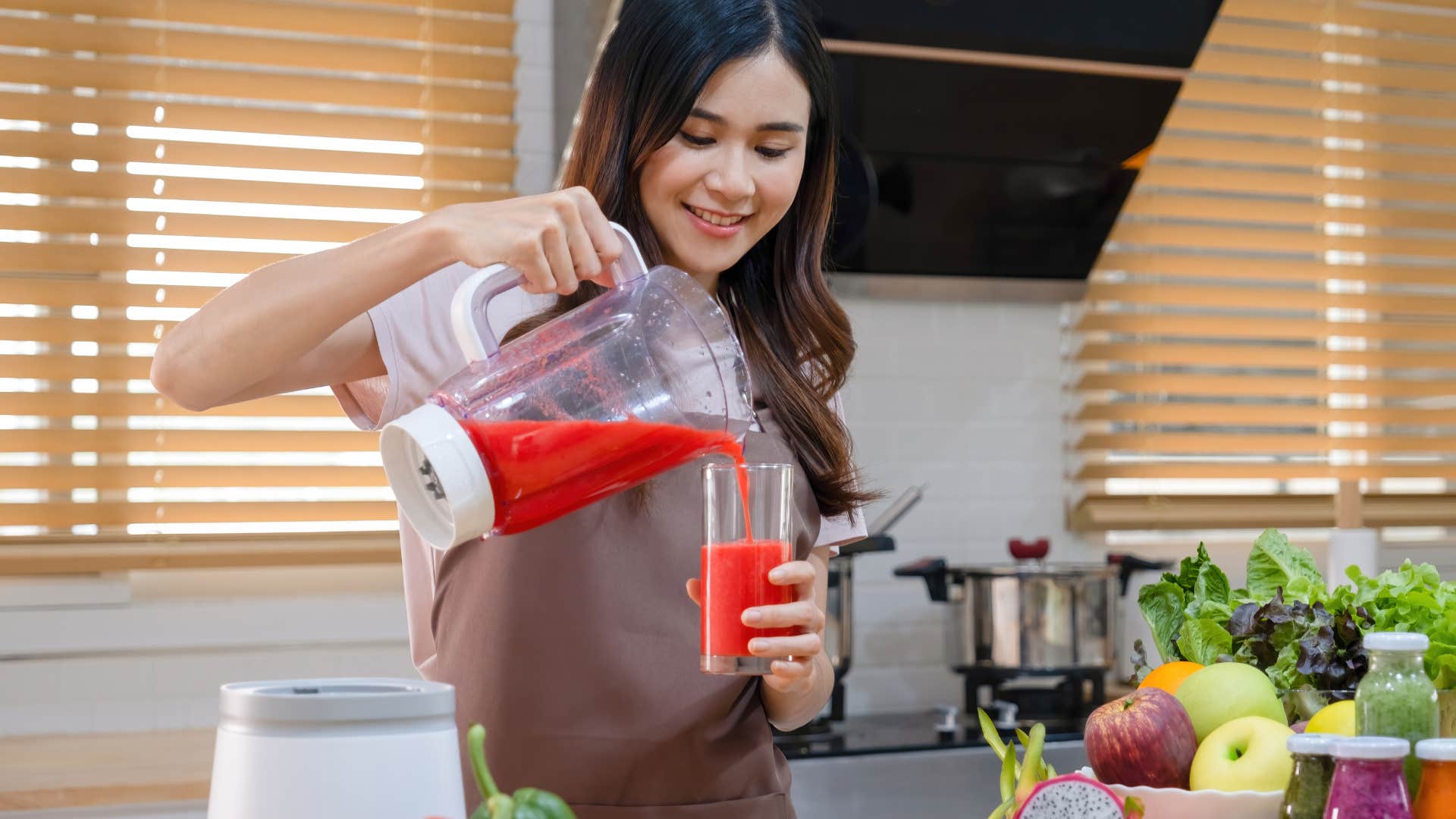woman pouring smoothie from blender into glass