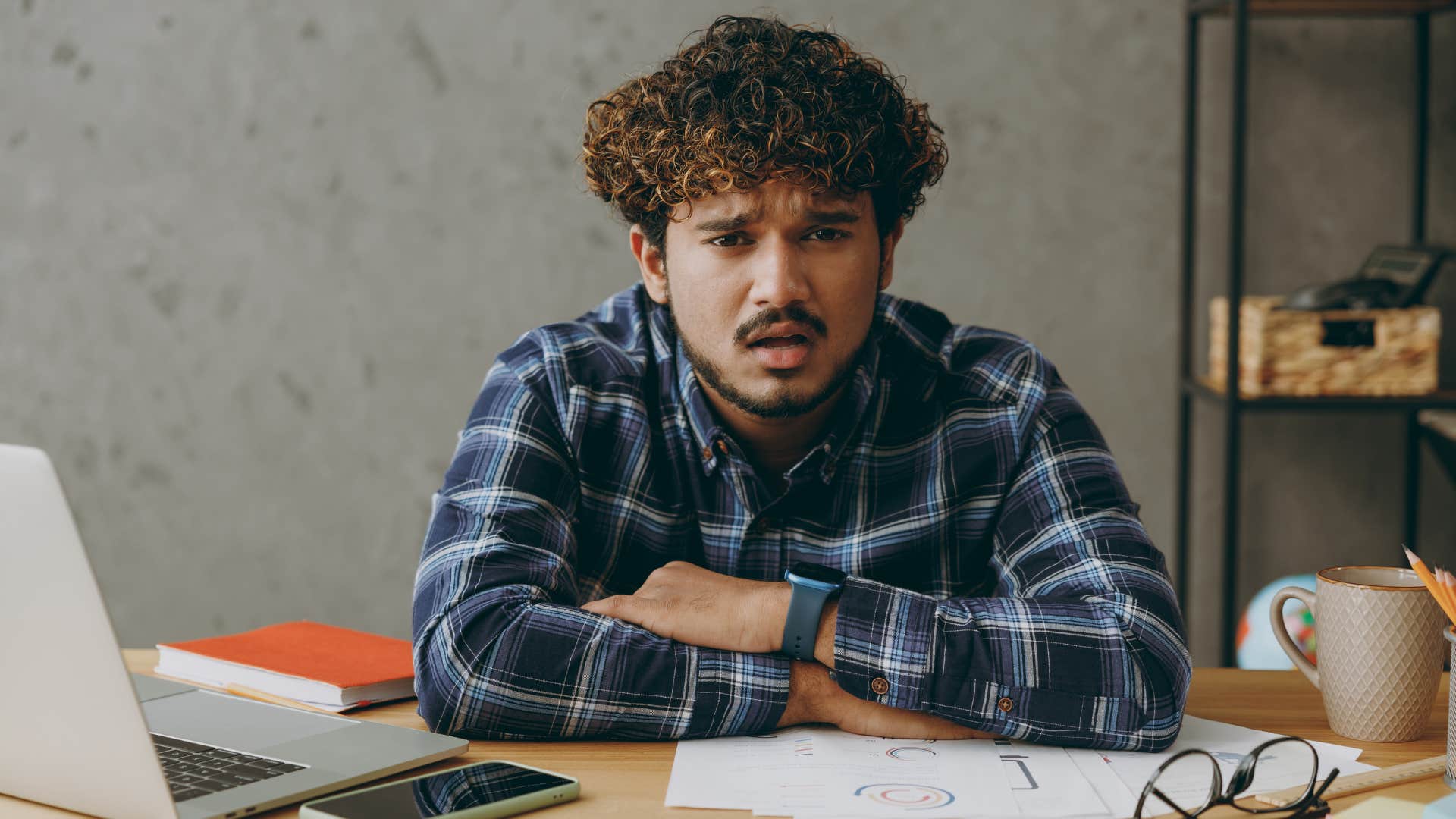 man in plaid shirt crossing arms and saying that's not my problem while staring at camera