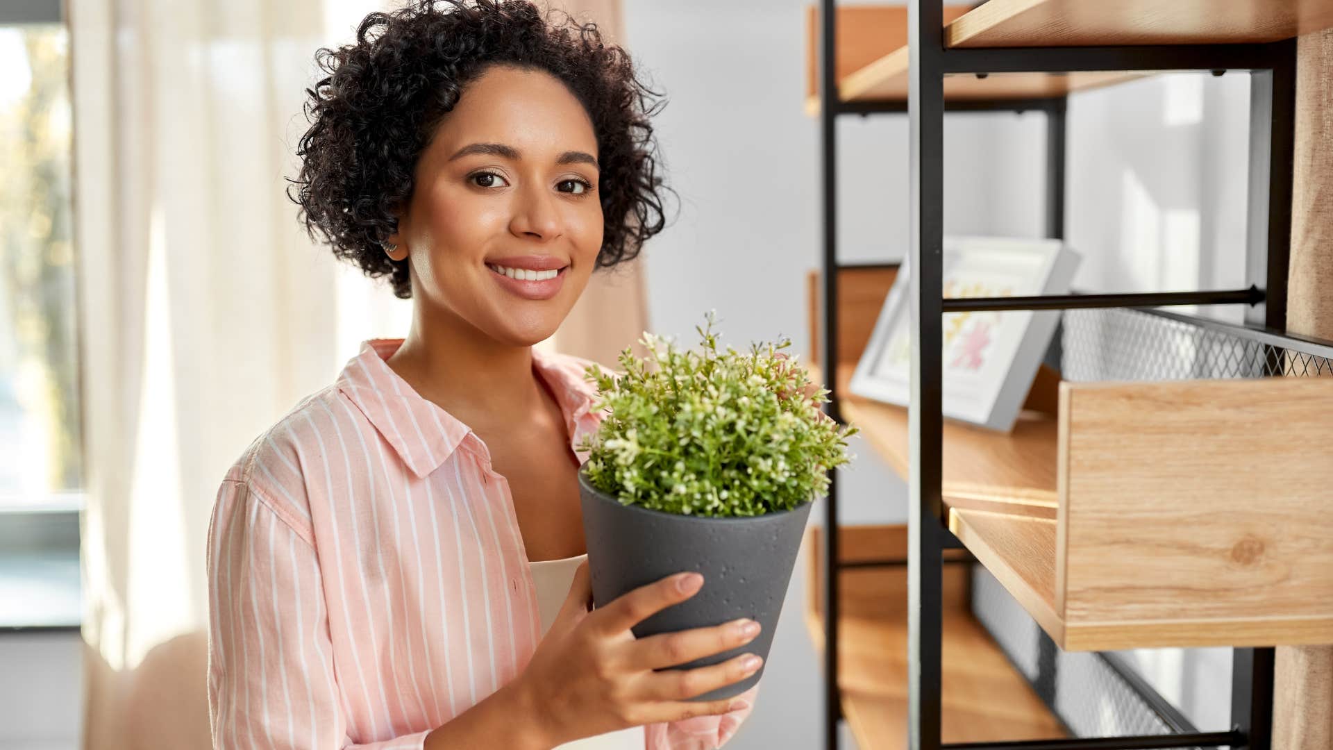 Woman holding fake plants at home.