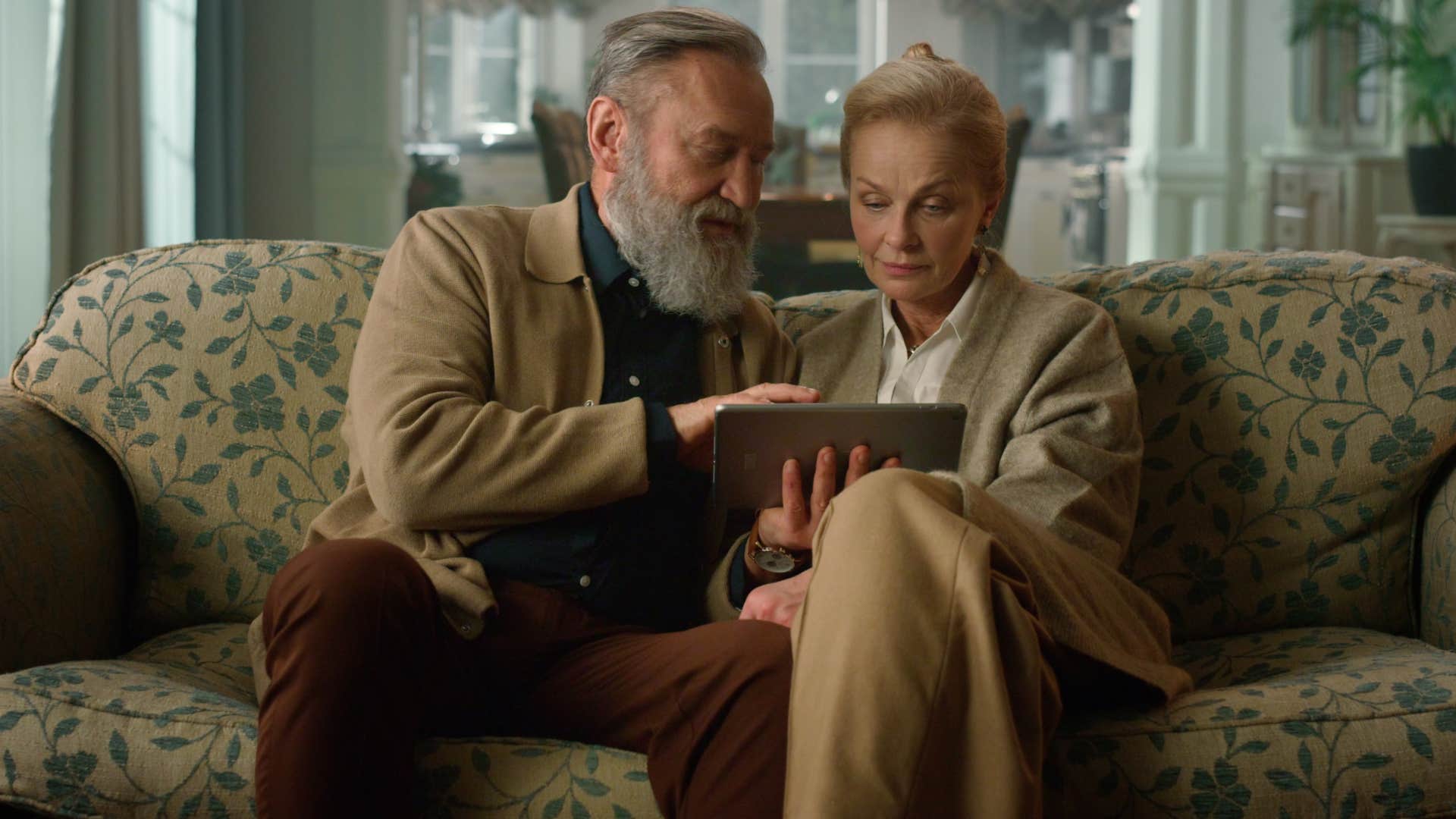 Older couple sitting on decorative furniture at home that no one's allowed to use.