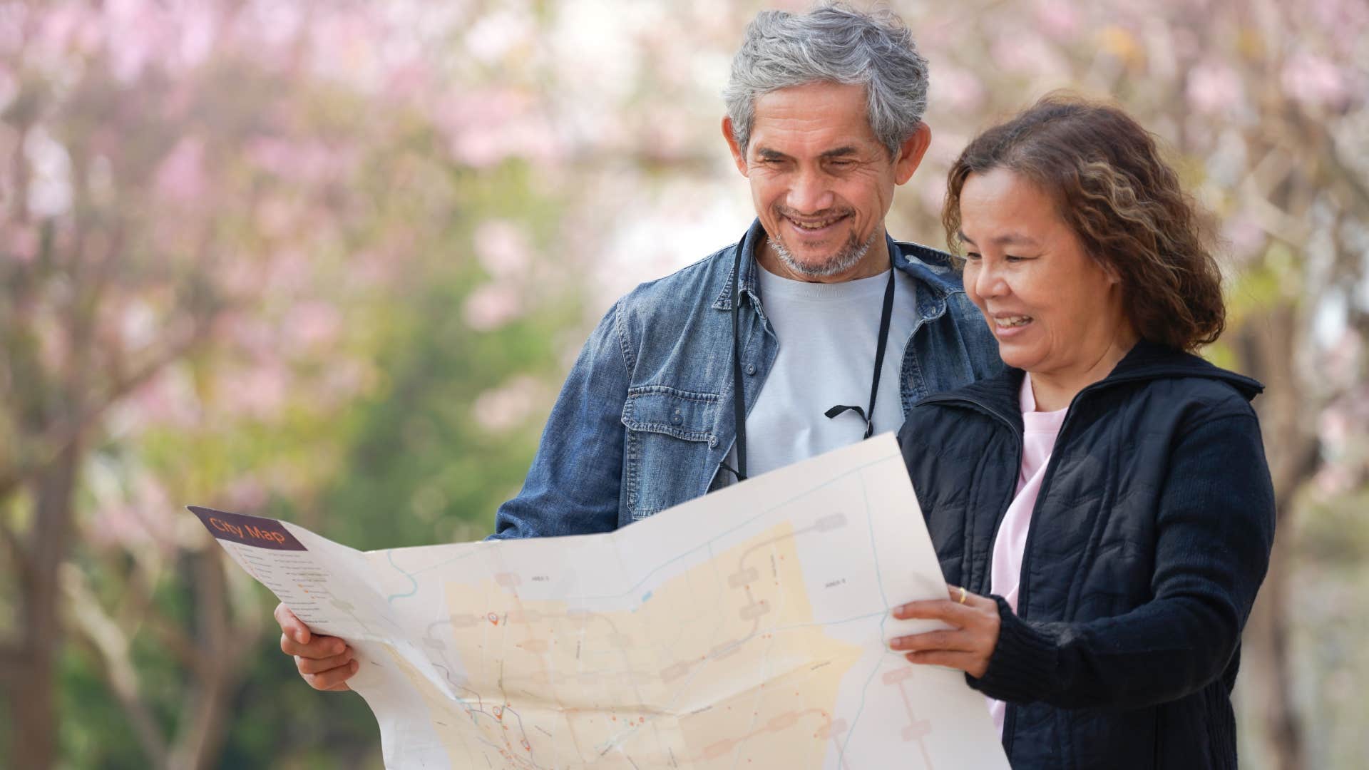 Older couple looking at paper maps outside.