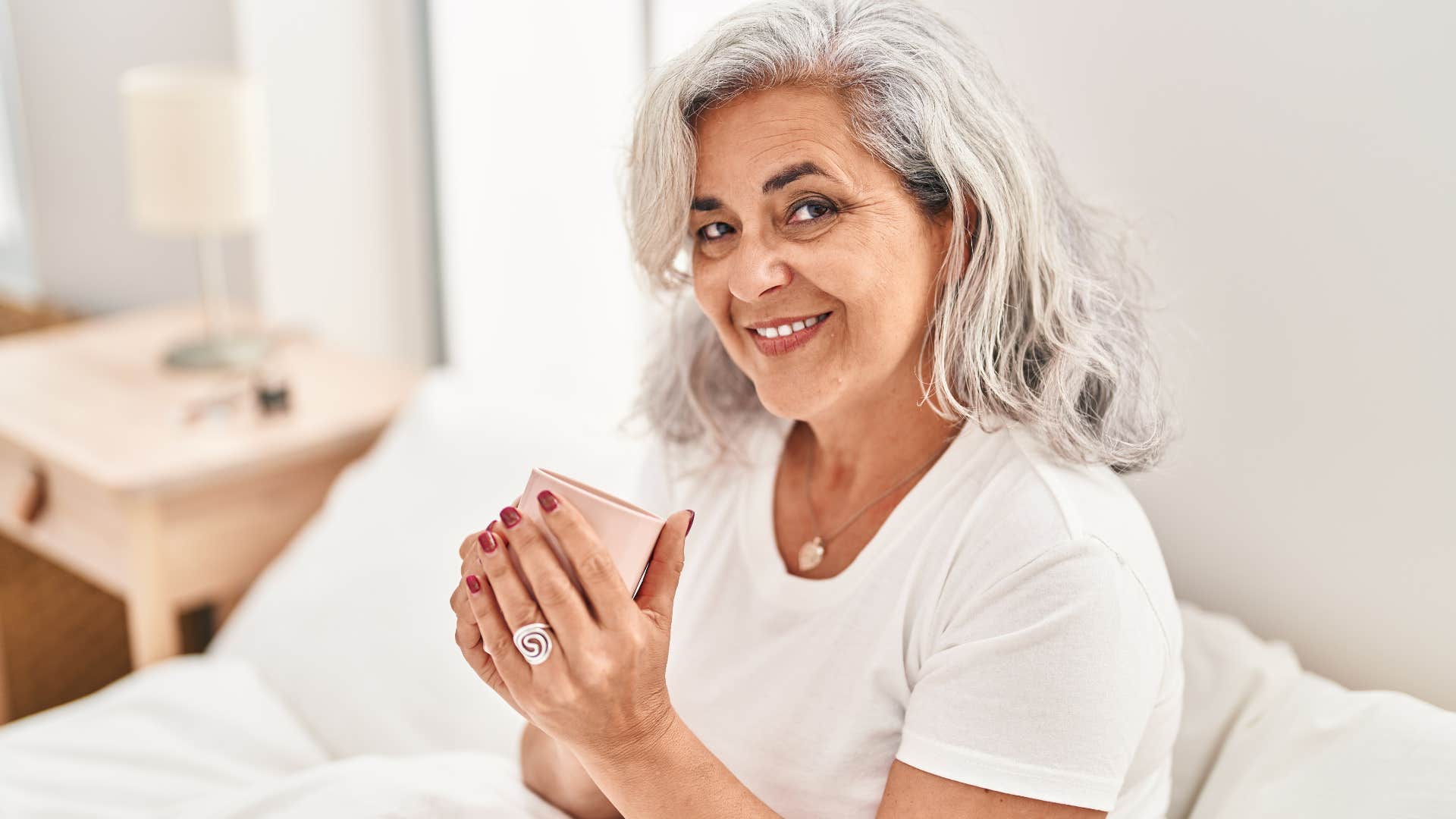 Woman smelling unlit candles at home.