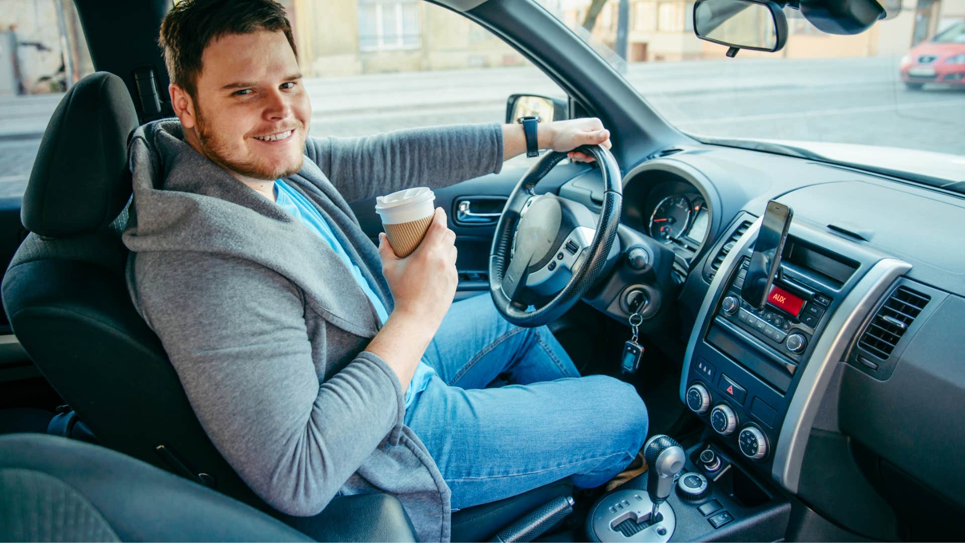 young man holding coffee while driving
