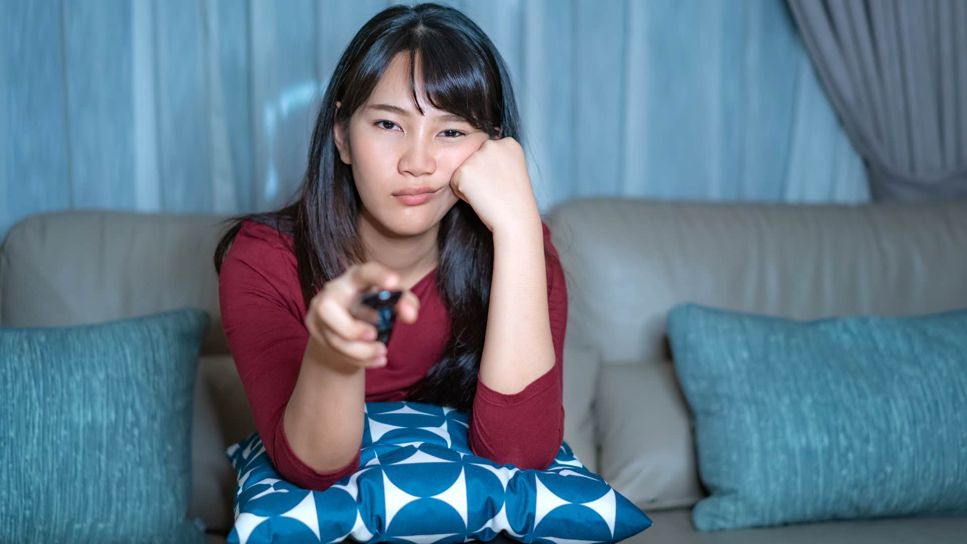 Woman watching mindless entertainment on her couch.