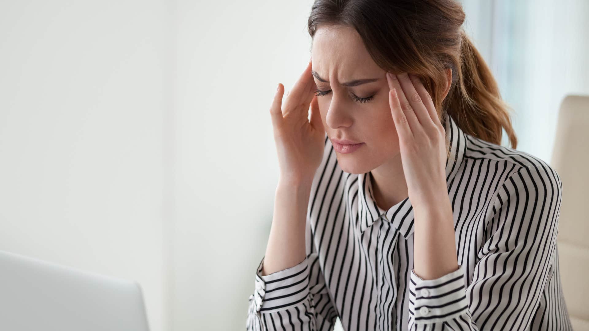 woman feeling discomfort and rubbing her temples