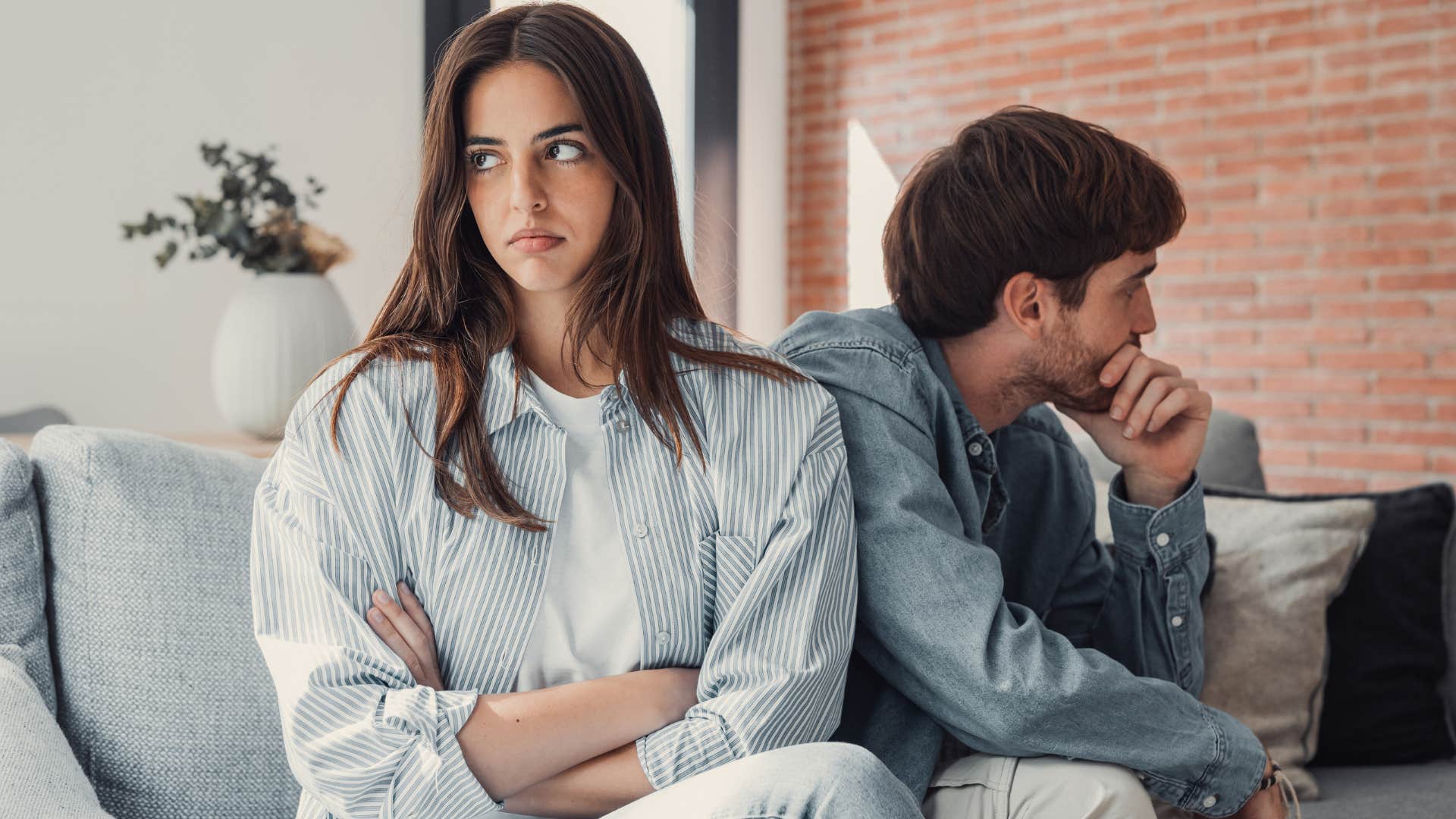 upset couple sitting next to each other in a room with bare walls