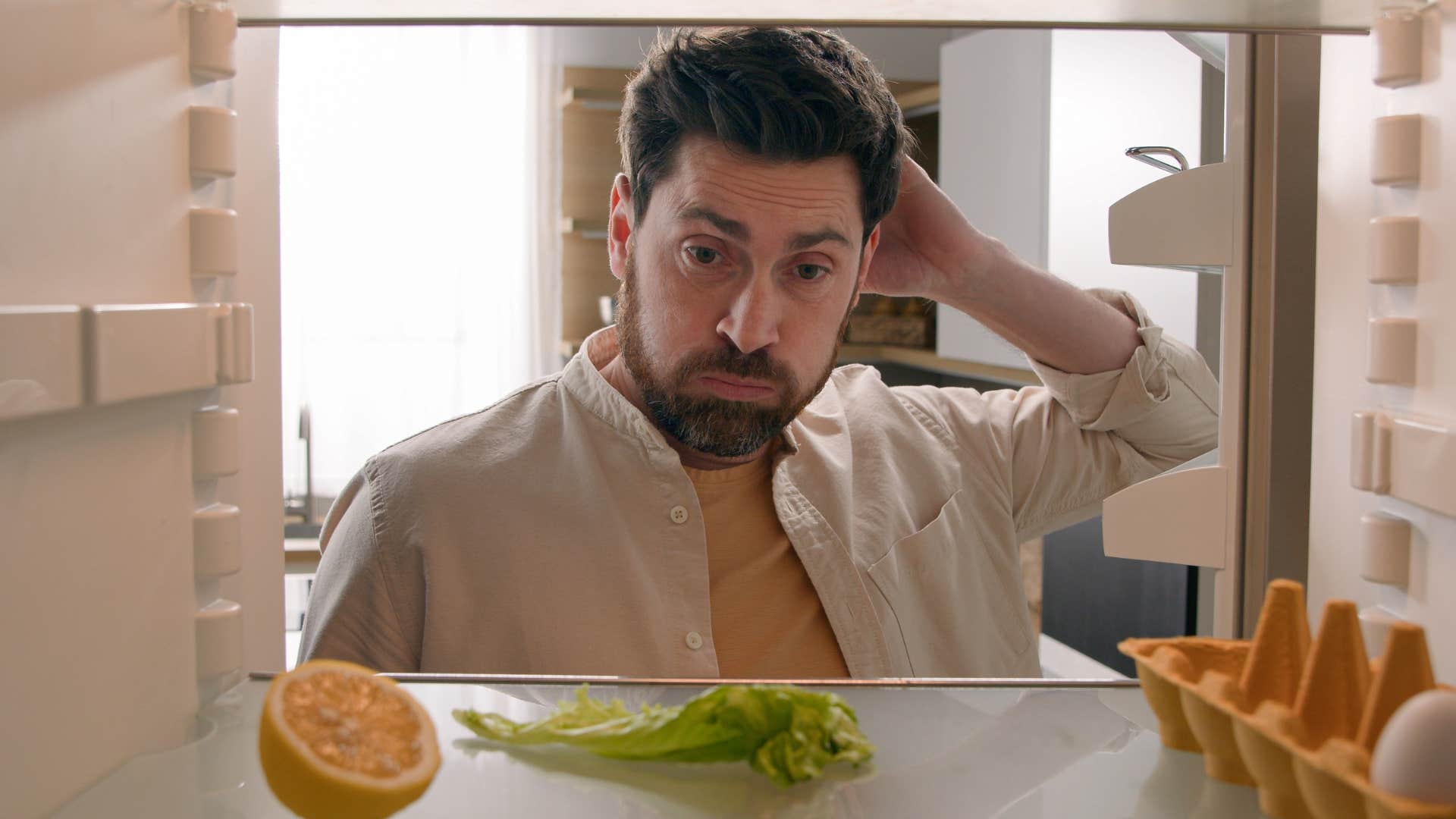 Man looking in his empty fridge at home.