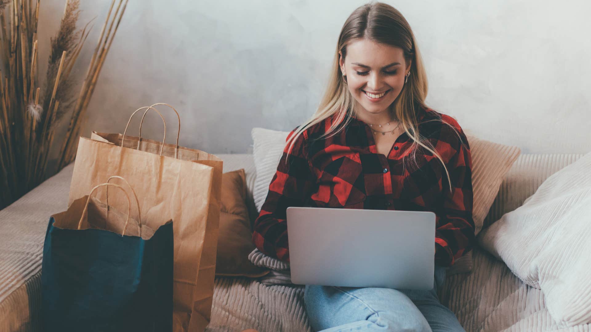 Woman sitting on the couch surrounded by random expensive purchases.