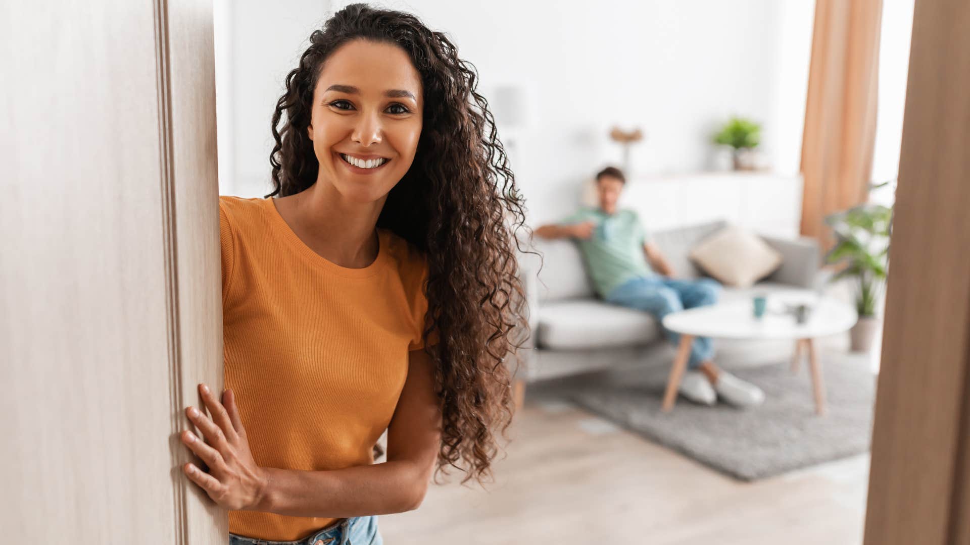 Woman opening a door and smiling with no mirrors around.