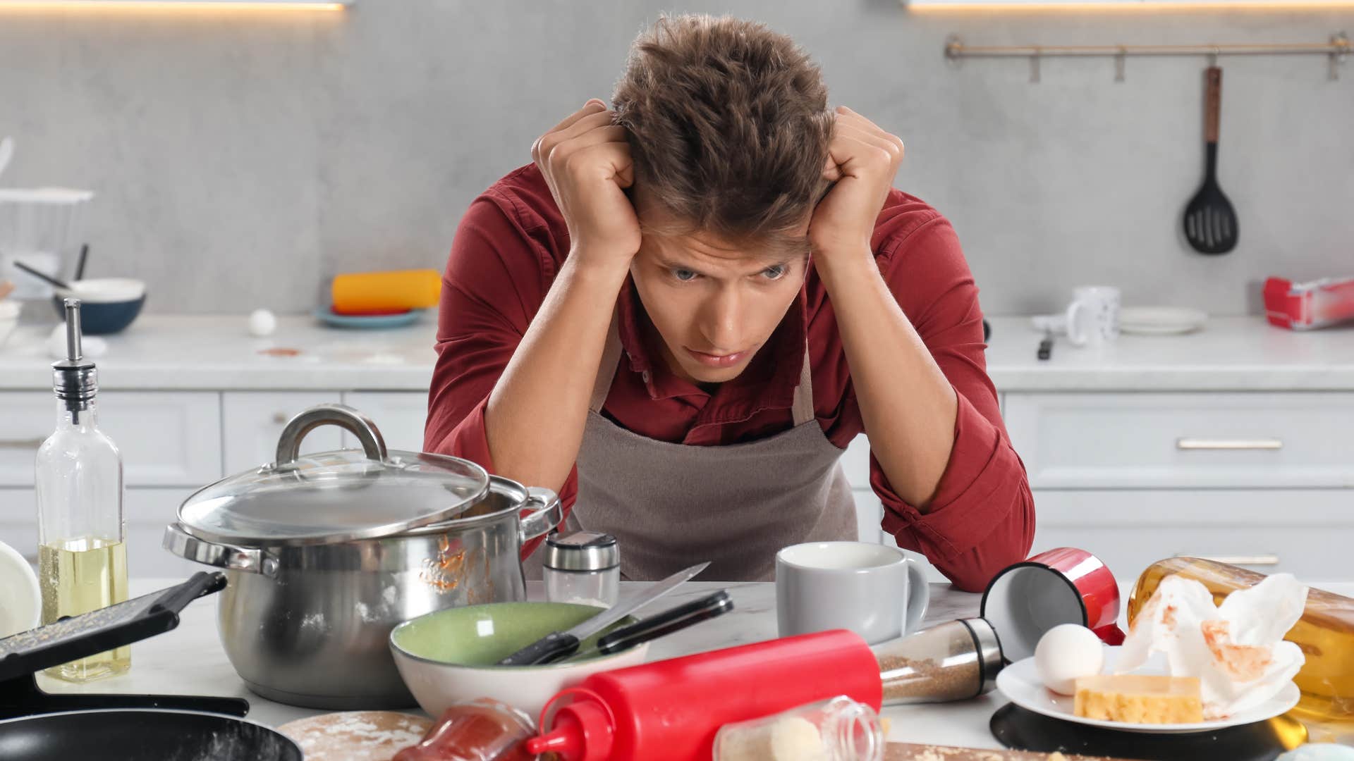 Man holding his head in his hands around half-finished chores. 