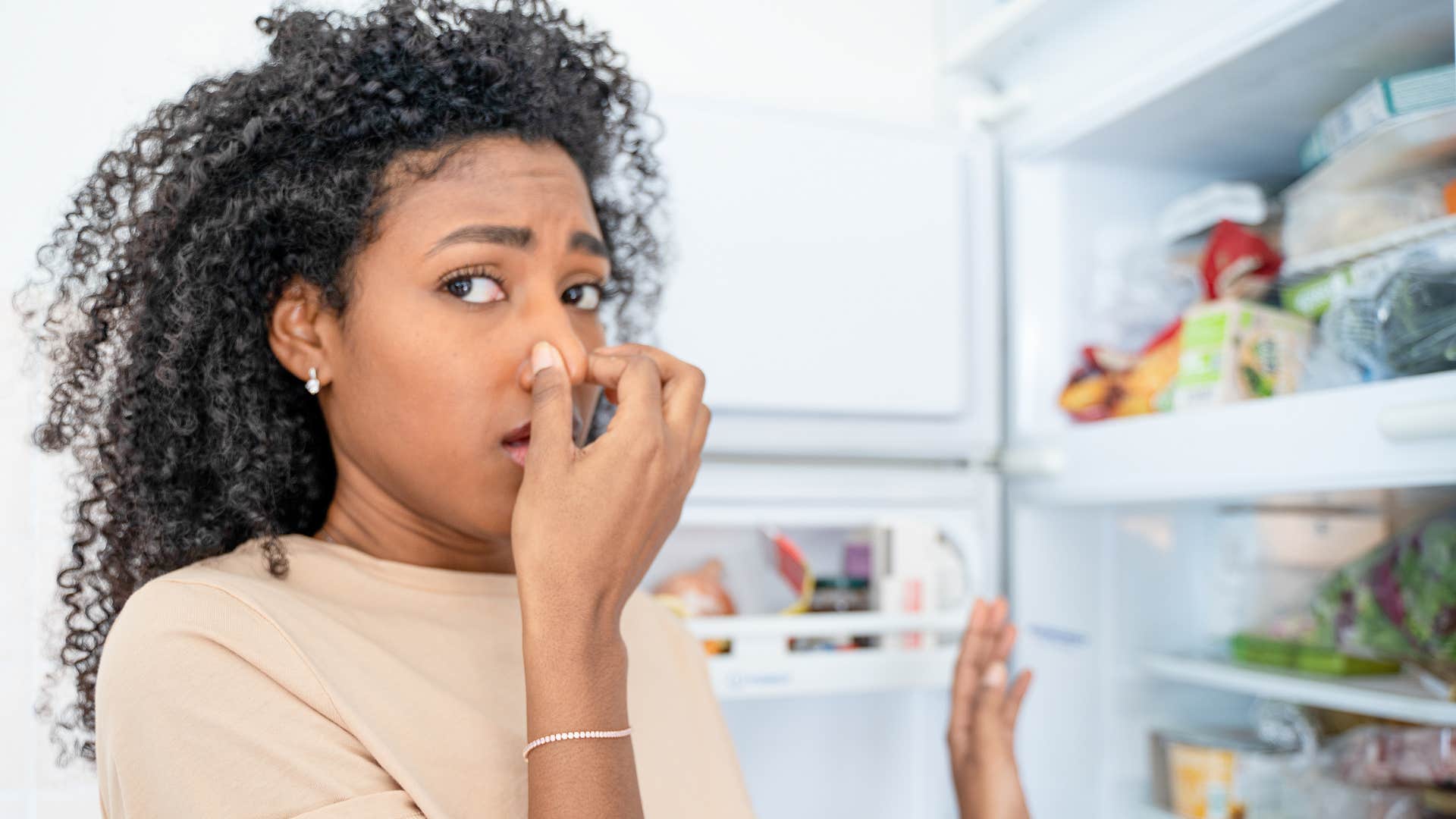 a woman cannot stand the smell from her fridge full of expired food