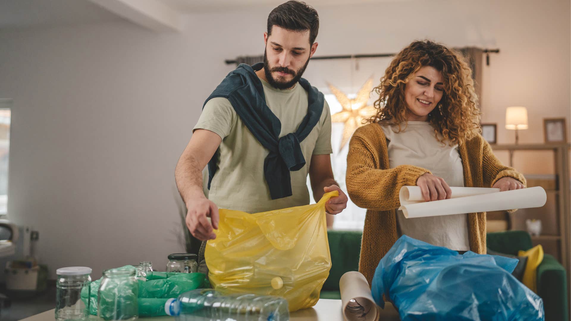 a couple throws their trash into bags rather than a solid trash can