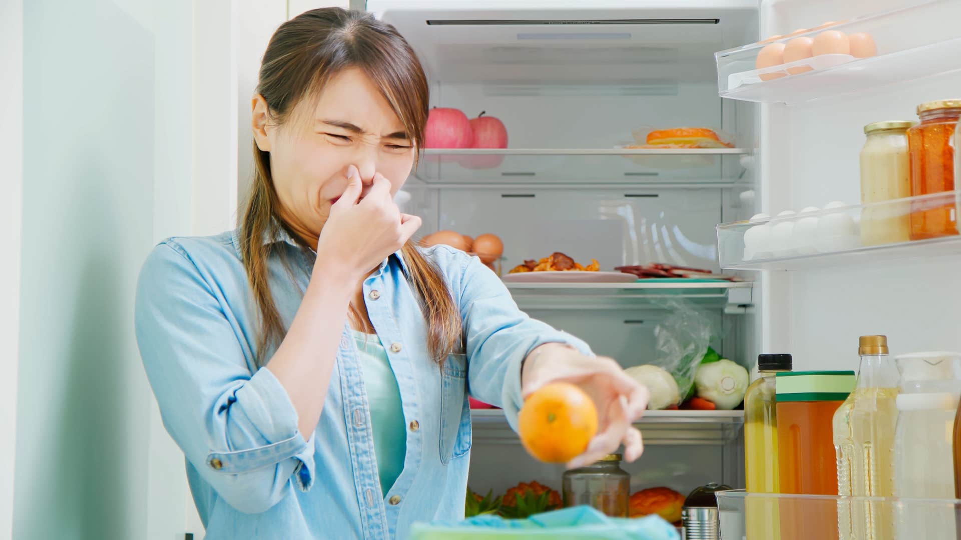 woman holding her nose throwing out expired food