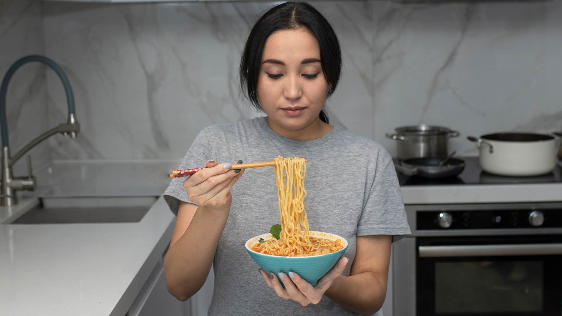 woman eating food lacking nutritional value in her kitchen