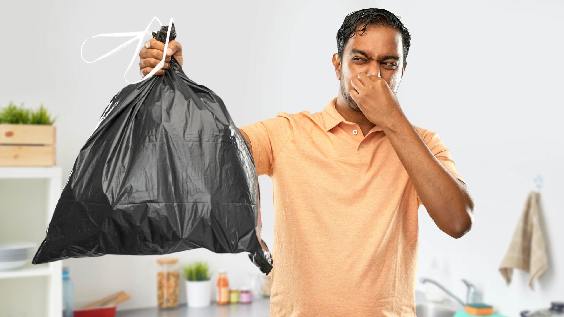 man without a trash can holding a smelly trash bag