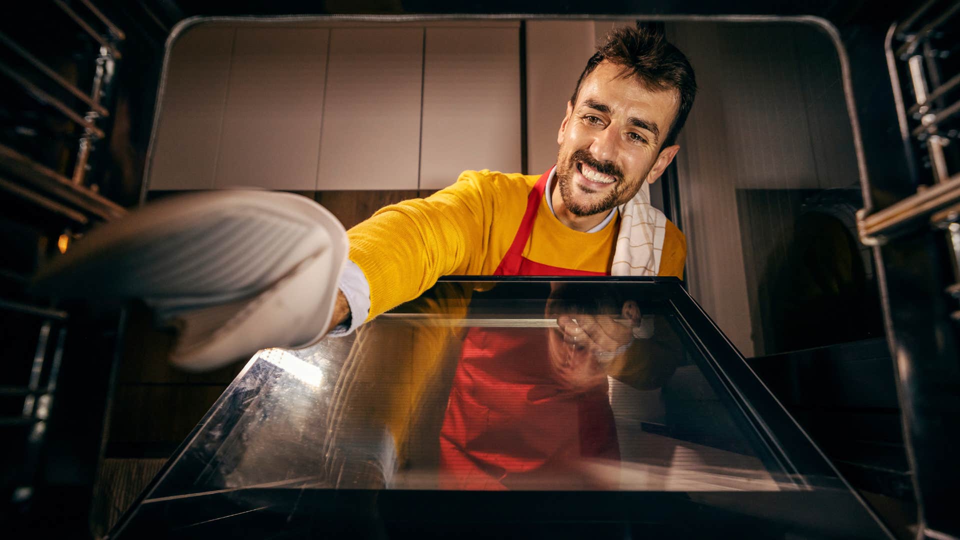 man putting storage in his oven at home