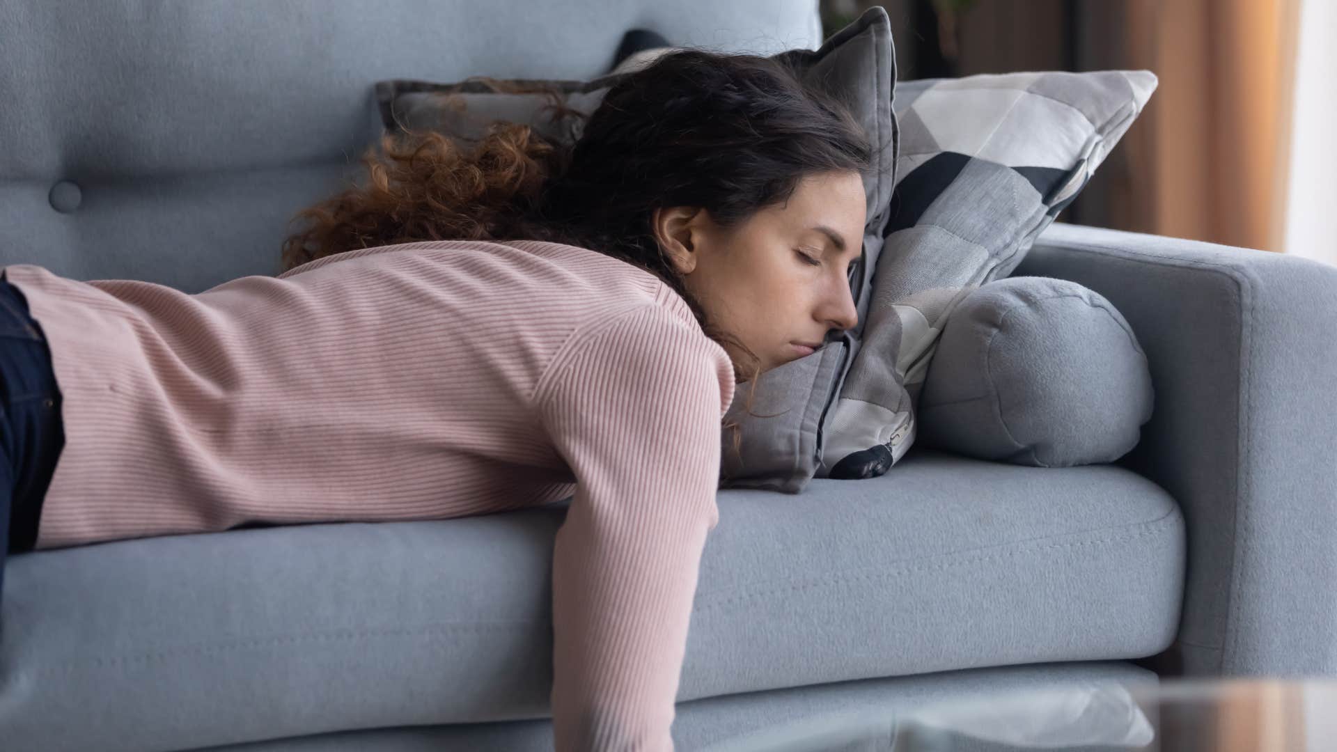 woman in pink shirt doesn't want to get up for the remote as she lays in sofa