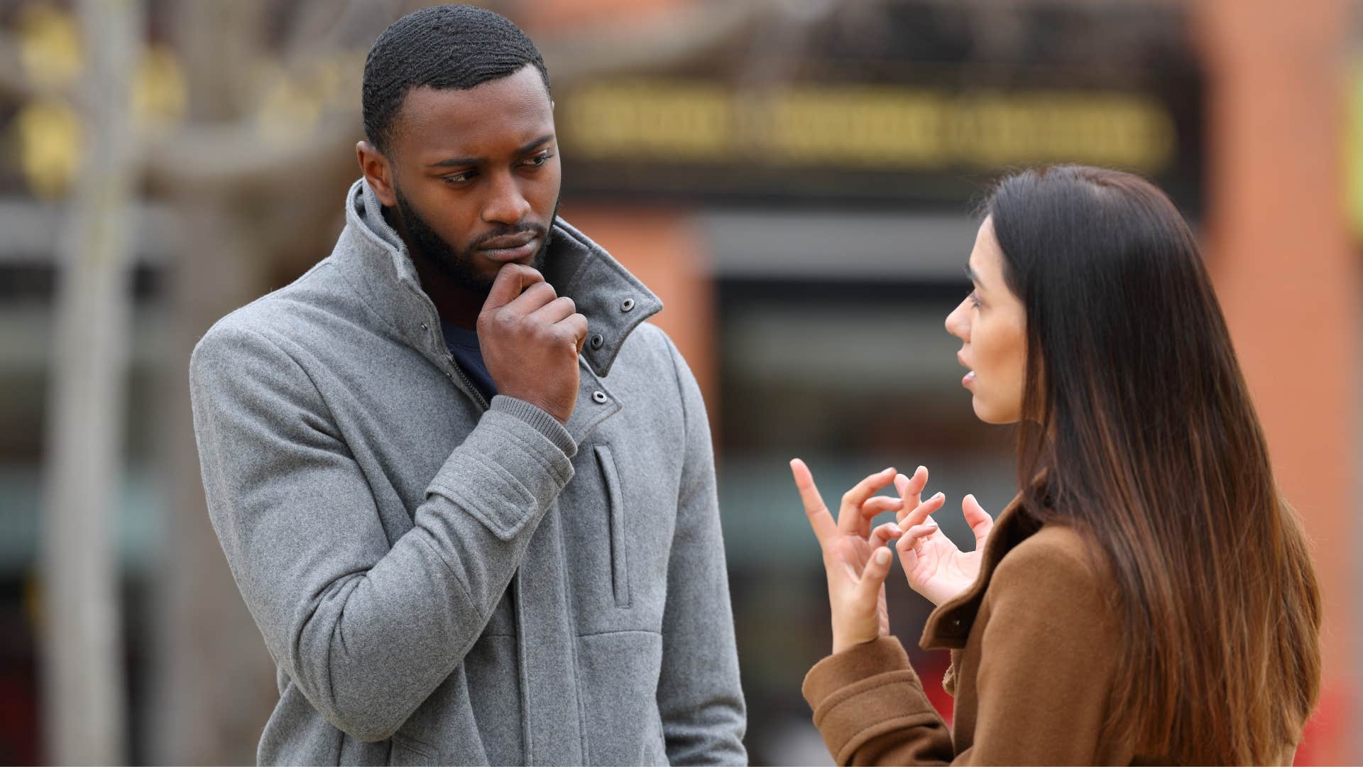 man in gray jacket saying interesting tell me more about it while woman in brown jacket continues talking
