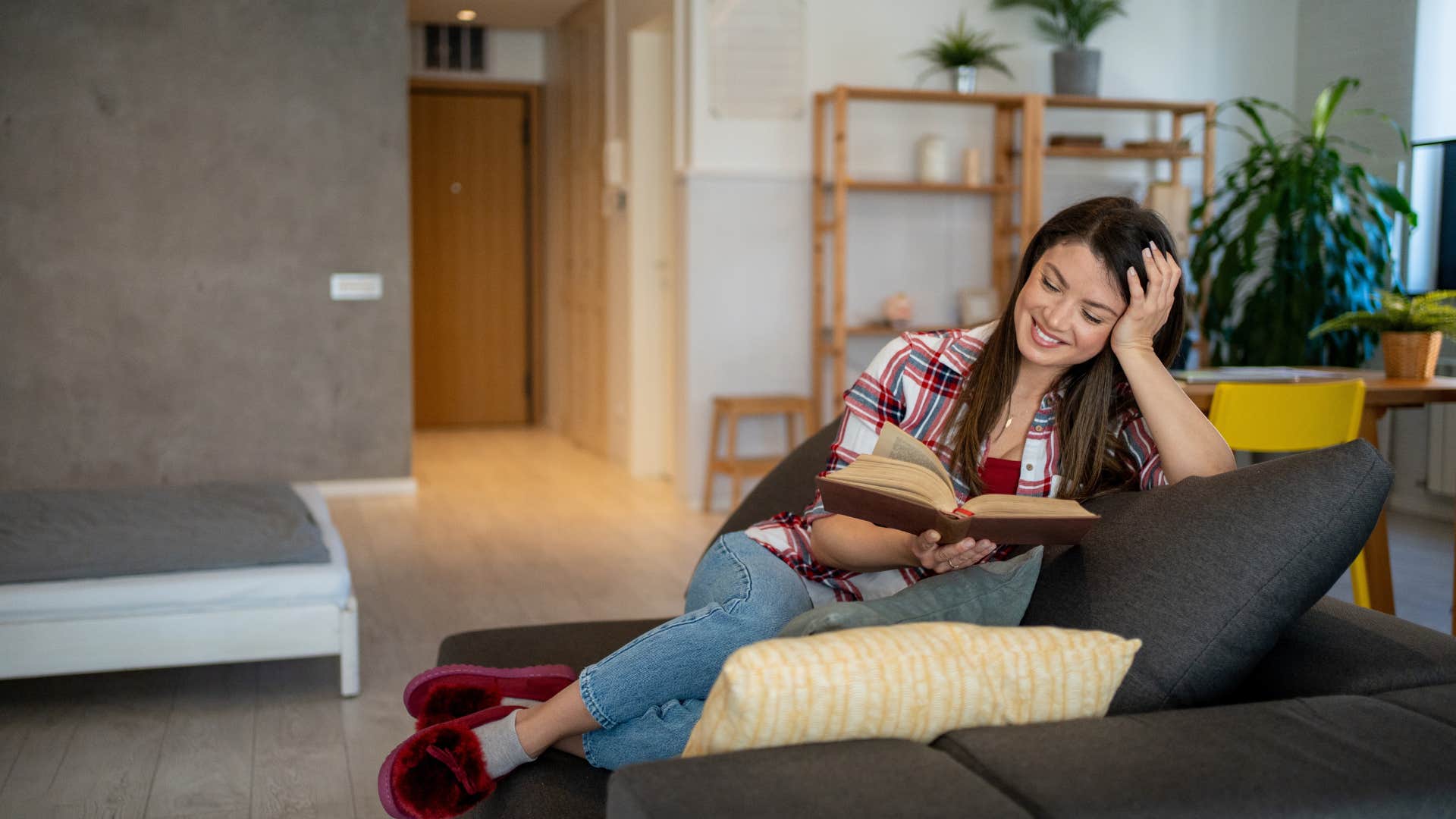woman wearing slippers sitting on couch reading