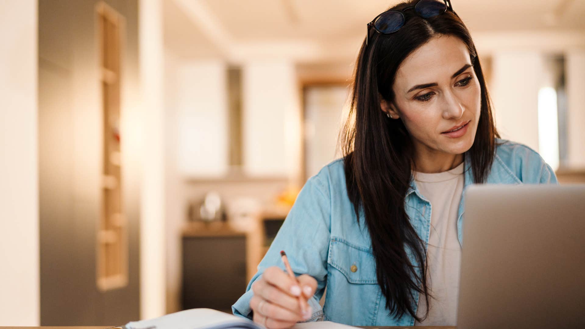 Woman writing in a shared calendar at home.