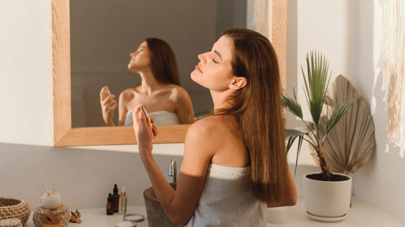 woman spraying perfume on her neck